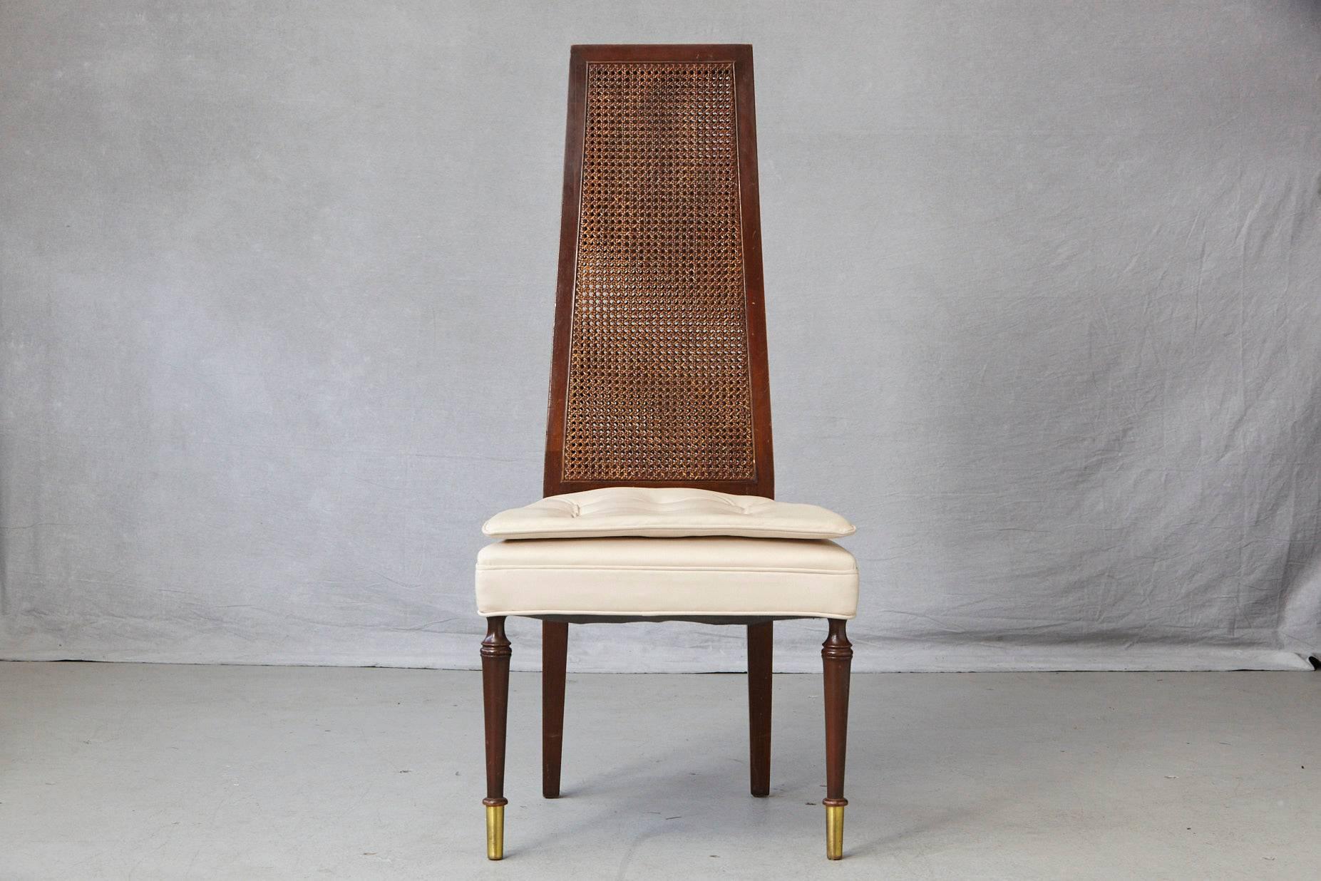High back desk or side chair with a double-sided rattan back and a double seat cushion in beige faux leather, mounted on round legs with brass tips to the front and square legs with a slight splay in the back. The double-sided rattan back is in very