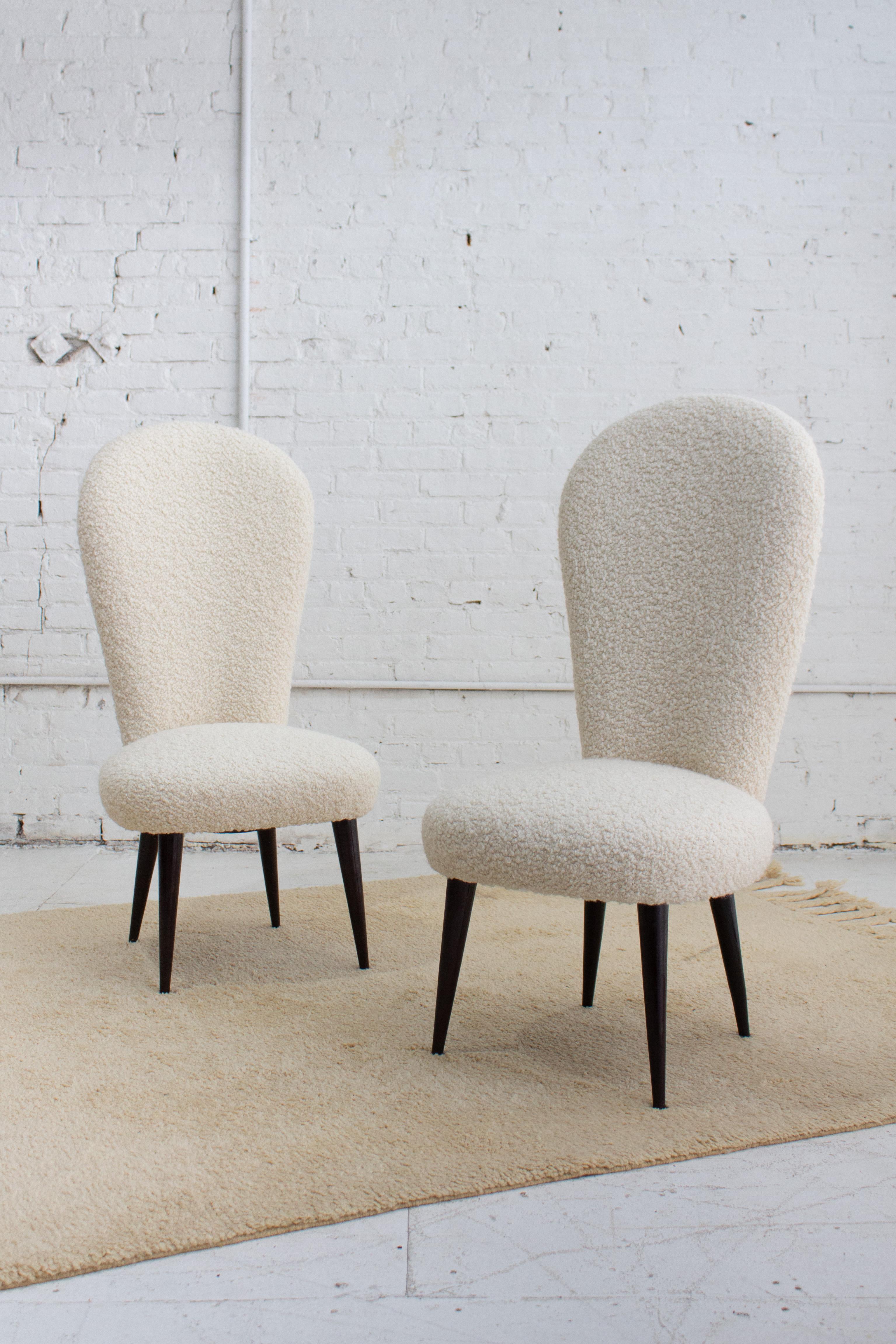 A pair of mid century Italian chairs newly reupholstered in a high quality wool bouclé. Curved high back silhouette with tapered dark wood legs. Petite in scale. Sourced in Northern, Italy.