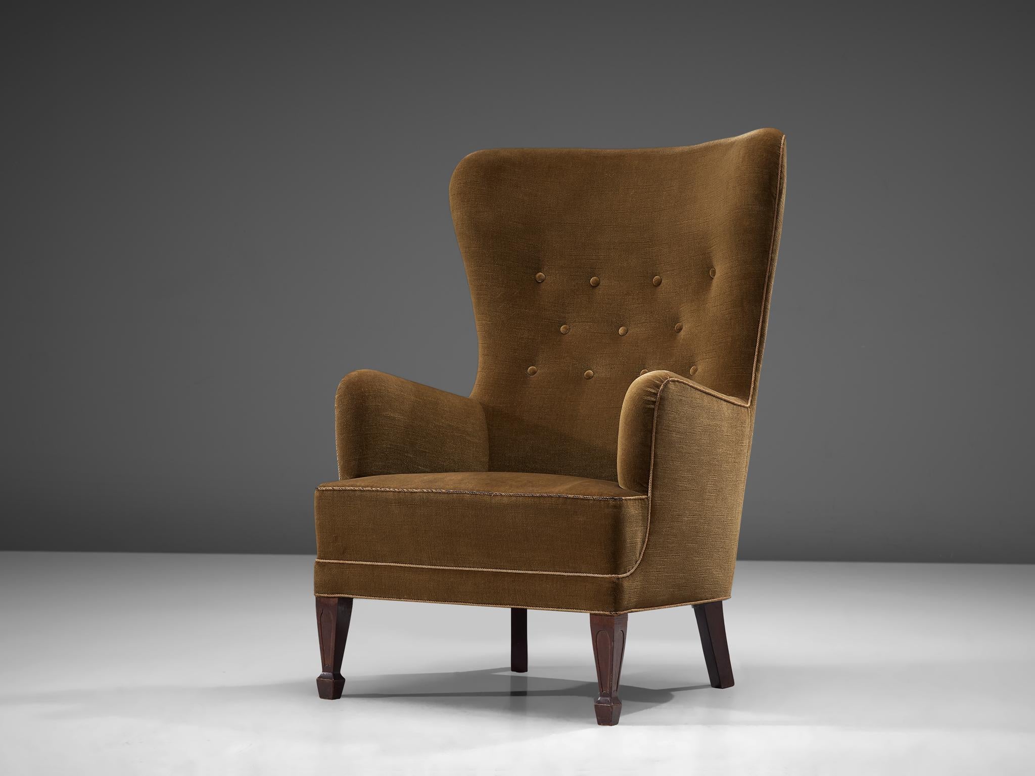 High back lounge chair by Frits Henningsen, Denmark, 1930s

This high back easy chair has legs made in stained mahogany. The seat, back and sides hold the original olive green woolen fabric.
The front legs show a refined detail, typical for the