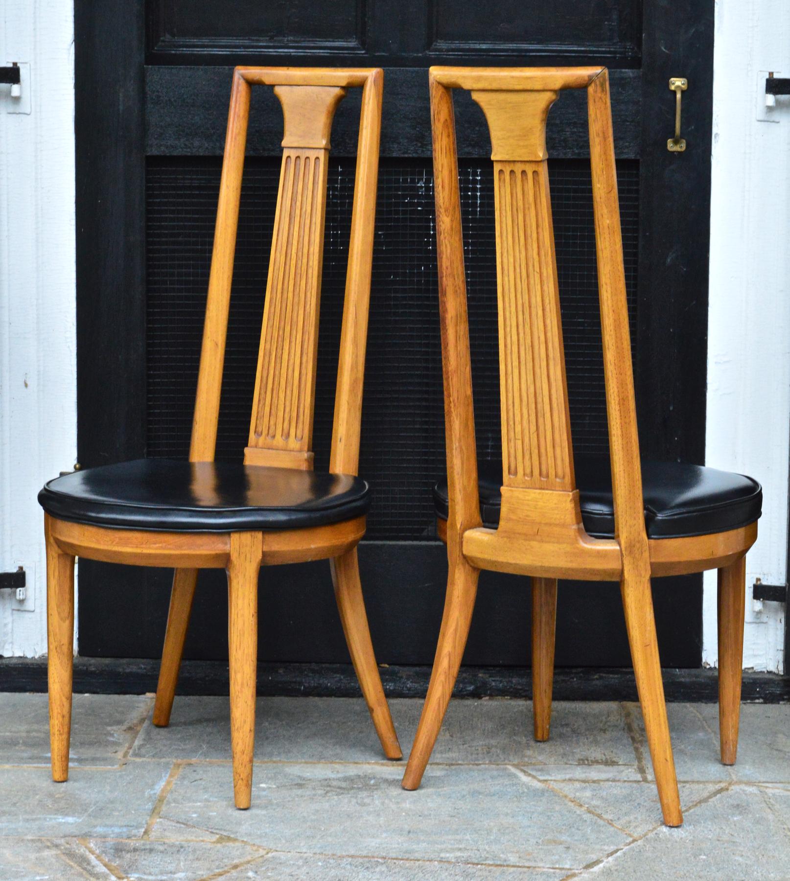A sexy and sophisticated pair of midcentury side chairs of ash by esteemed maker Tomlinson. Ample rounded seats of original black leatherette combined with the dramatic high back of this chair makes it particularly stylish.