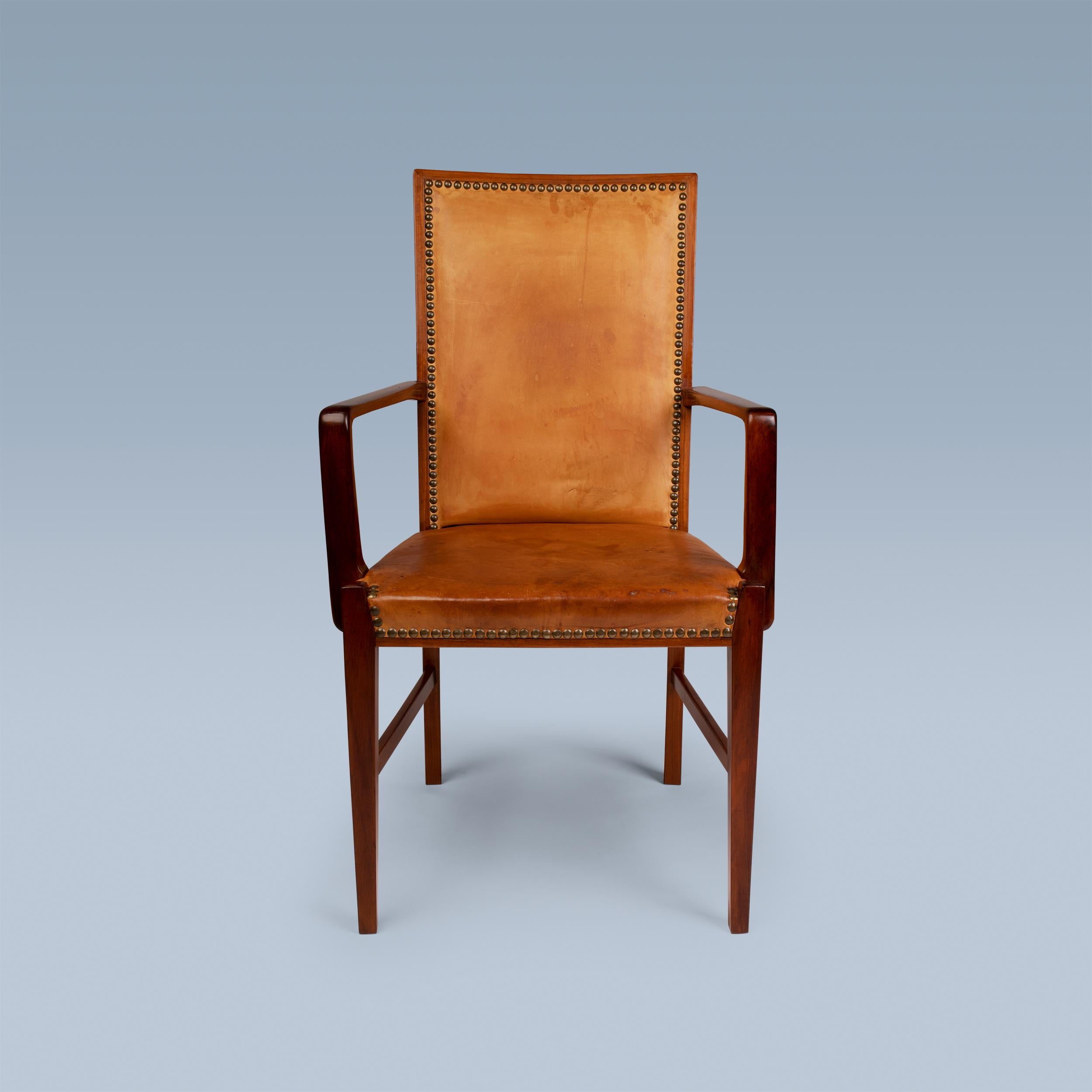 This highback armchair by a Danish cabinetmaker has a frame of nutwood.
It is upholstered with patinated leather and fitted with brass nails.
Ideal desk chair or head of the table chair.