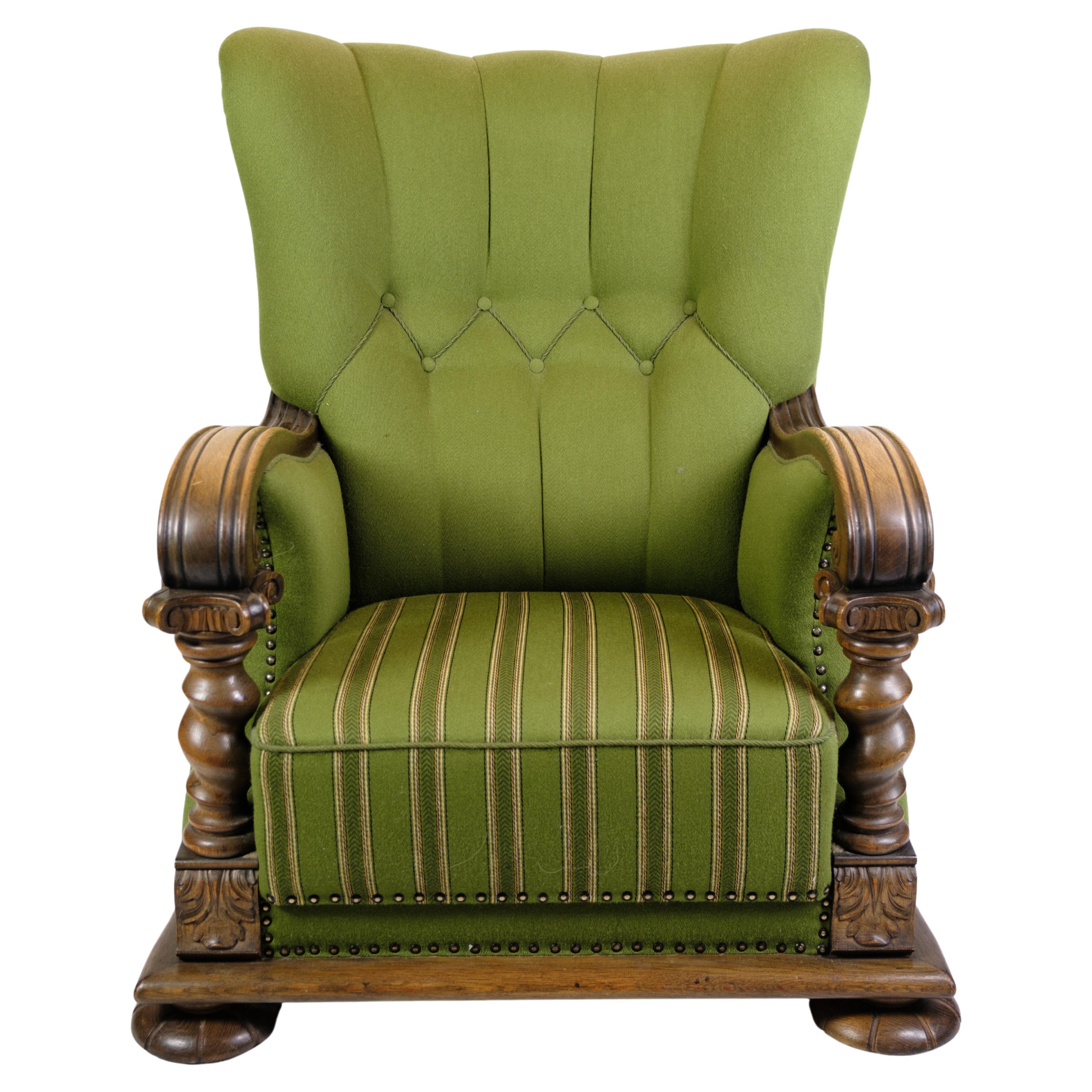 Hochlehniger Sessel in grünem Stoff mit Holzschnitzereien aus den 1920er Jahren.