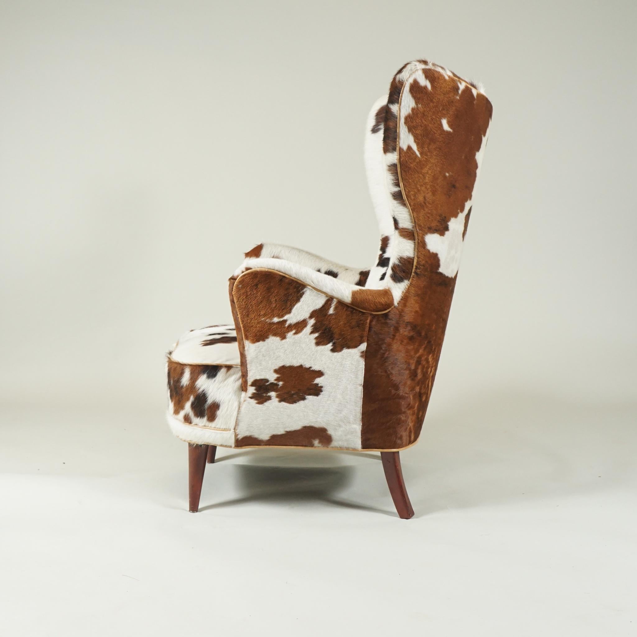 HIgh-backed Danish modern armchair from 1930s, organically shaped for comfort, newly recovered in
a soft brown and off-white cowhide. A new twist on a Classic style.