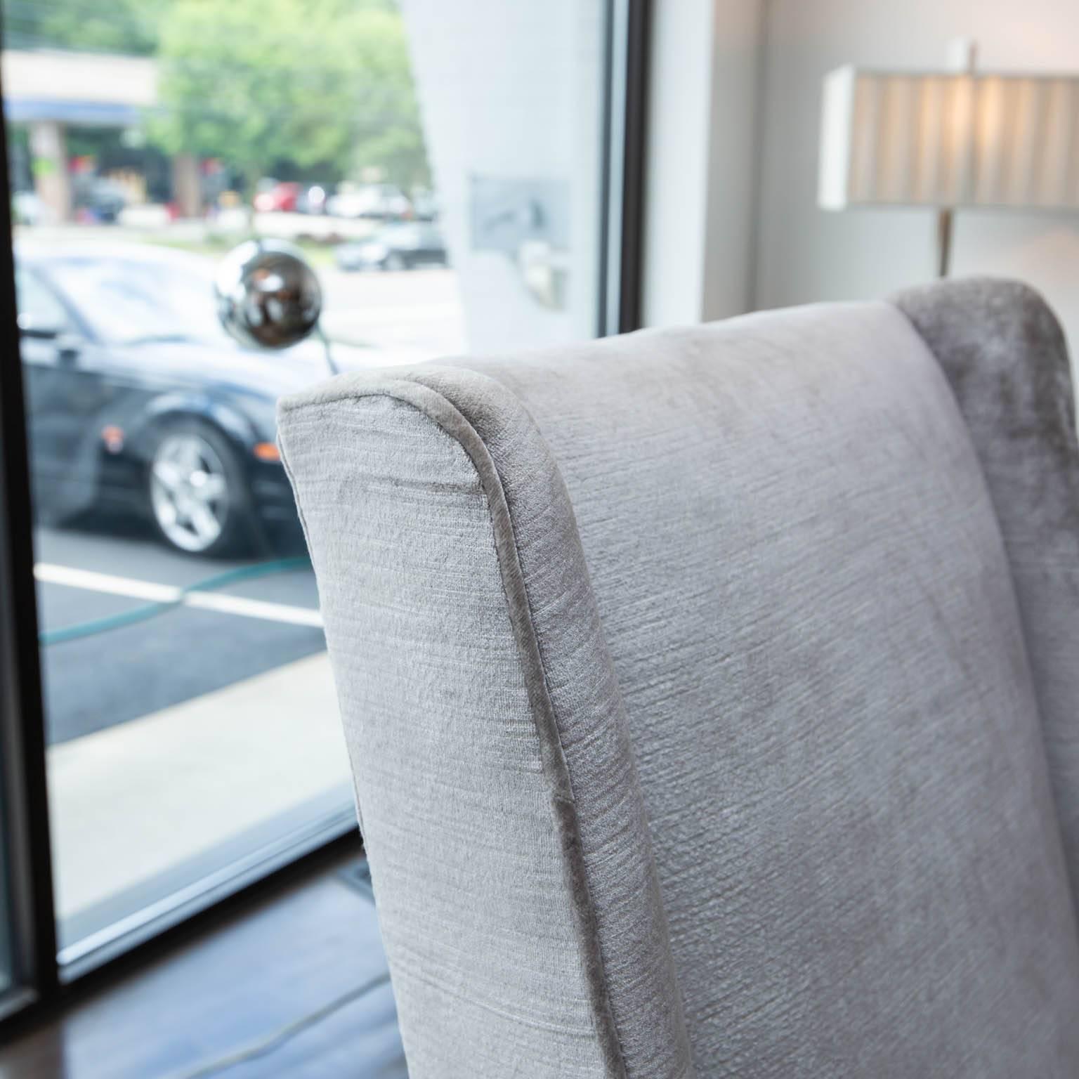 Set of high back chairs from the 1950s redone in a neutral gray velvet. Tapered mahogany legs.