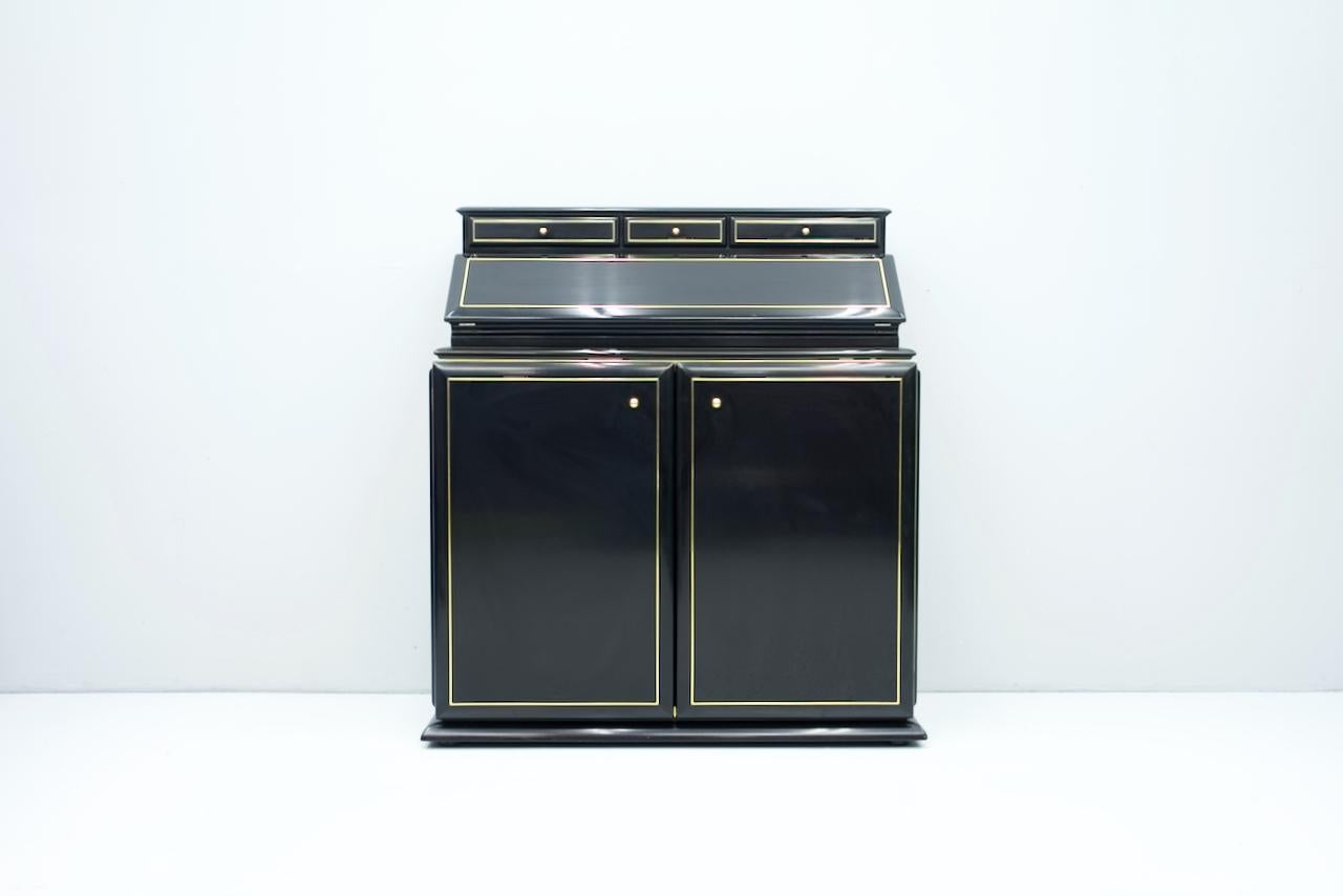 Very high quality secretary in black glossy lacquered wood and brass. Lots of brass. Very many very nice details. A large flap to open the secretary, inside equipped with black leather, a compartment inside to open, three drawers and two large
