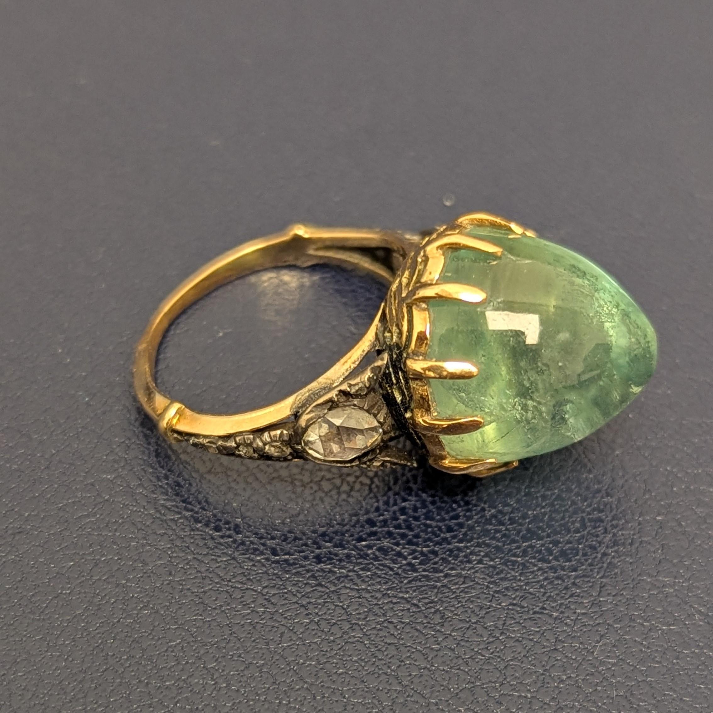 This ring features a powerful, prong-set, high-domed circular cabochon emerald, measuring approximately 12.70 x 13.20mm, with shoulders set with rose-cut diamonds, mounted in silver and 14K yellow gold.