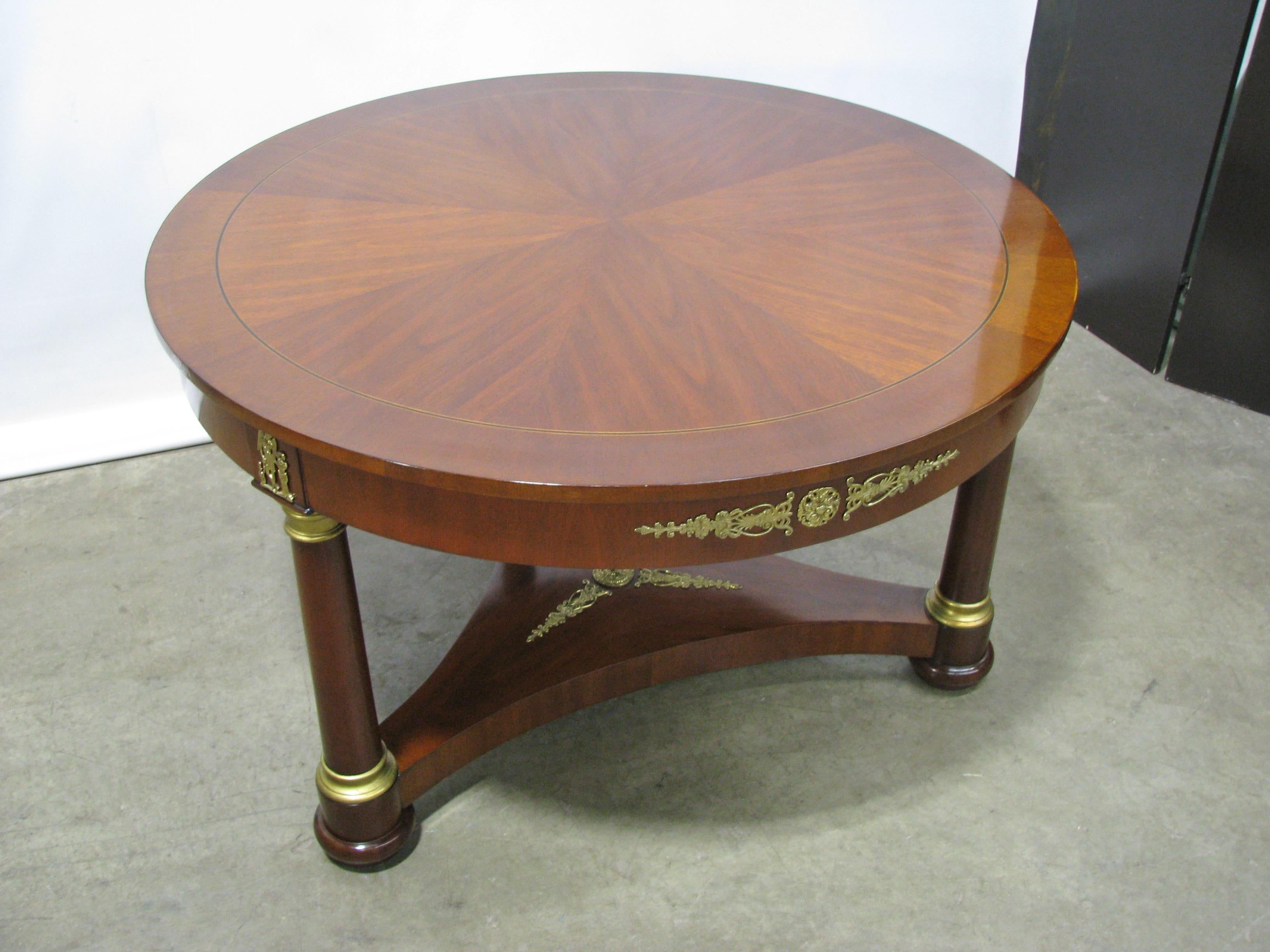 Gueridon style center table in the French Empire taste with wedge-shaped veneers. Mahogany solids and veneers, with cast brass neoclassic-style mounts. The capitals and bases on the three columns are gilded wood. Beautifully patterned veneers on the