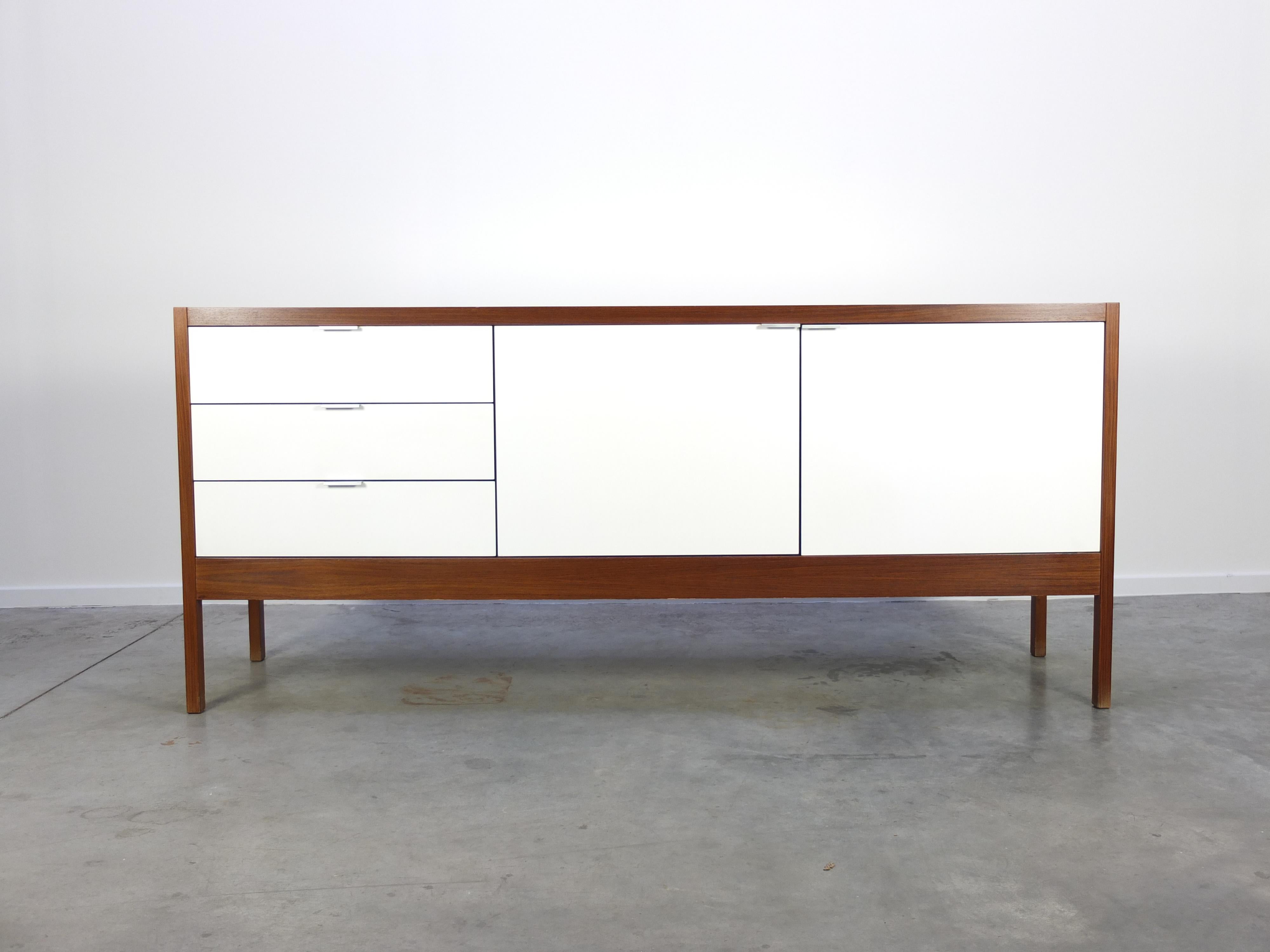 A special high-end sideboard from the ‘Series 3’ designed by Dieter Waeckerlin in 1963 for his Swiss company Idealheim. It has a solid walnut frame with a white laminated front, top and back. It features three drawers on the left and 2 doors on the
