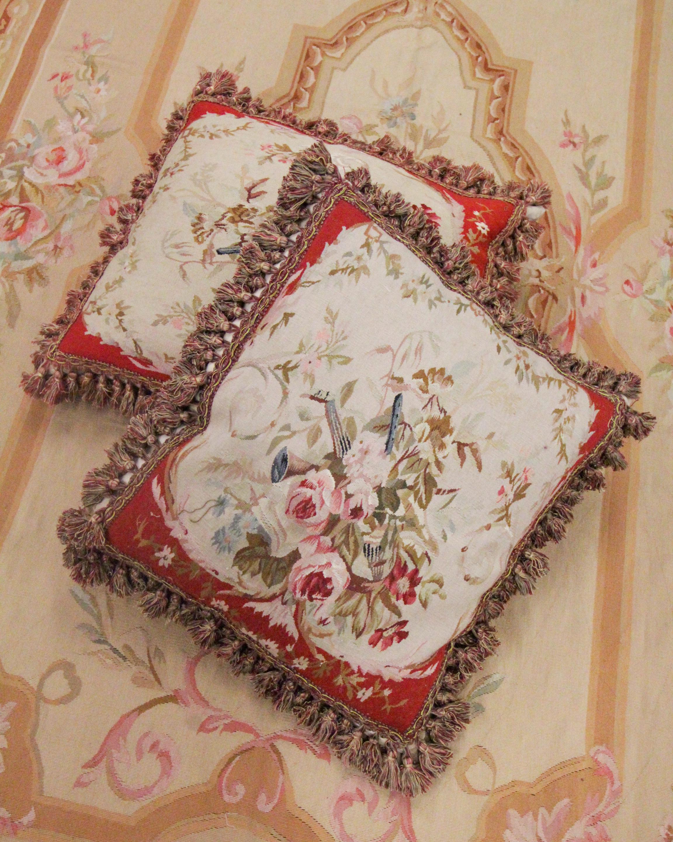 This graceful cushion cover is a handwoven Aubusson piece woven by hand with locally sourced hand-spun wool and cotton. The design features a subtle cream background with floral patterns that decorate; a rich red frame then encloses this. The design