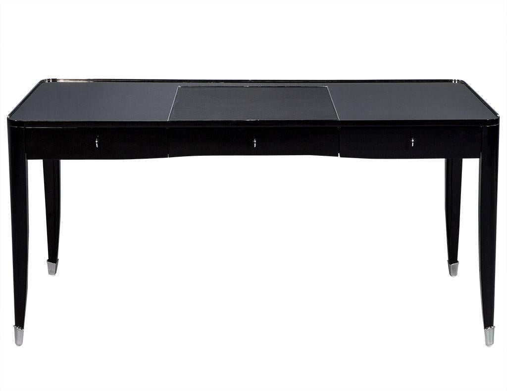 High gloss black lacquer writing desk with stainless steel accents. This 1920s inspired French desk features high gloss polished black lacquer and a gorgeous leather inset writing surface. It is simple, practical, and uniquely elegant. Complete with
