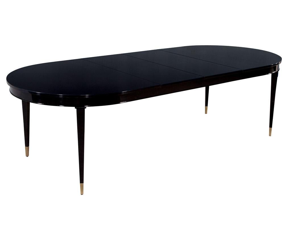 High gloss black lacquered mahogany dining table, hepplewhite inspired. Beautiful high gloss black polished finish on flamed mahogany woods. Composed of solid mahogany tapered legs with brass caps. Table is brand new and made in the USA, includes 2