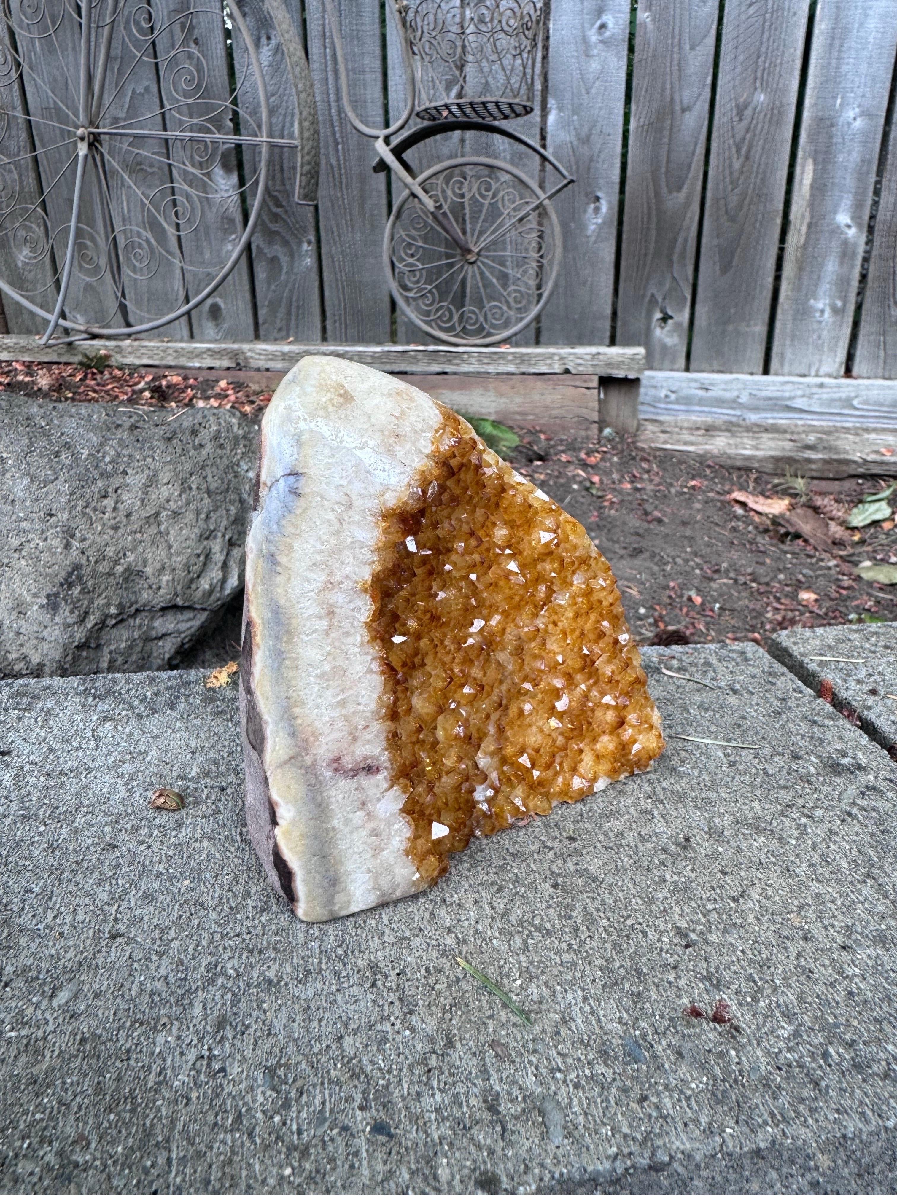 Questo geode di citrino, selezionato dai ricchi giacimenti minerari dell'Uruguay, emana una calda luce dorata. I grappoli di cristallo formati naturalmente da questo pezzo unico creano un effetto visivo straordinario, rendendolo un'aggiunta perfetta