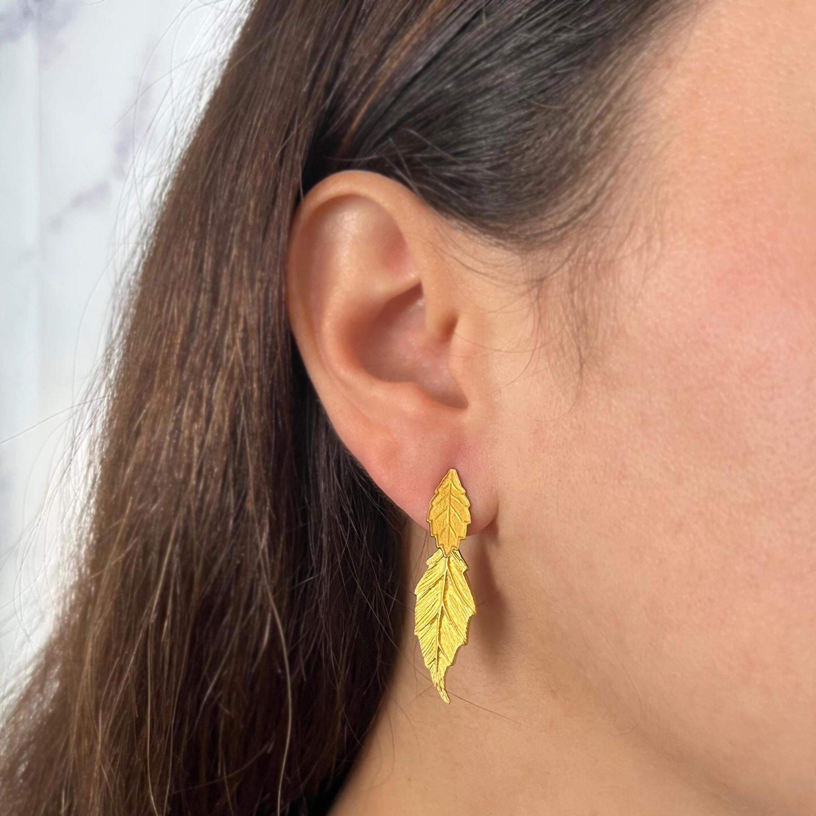 Orecchini a goccia in oro giallo 18 carati con texture opaca e design in 3 parti. La foglia più corta pende davanti al lobo dell'orecchio e quella più lunga dietro. Lungo 1,5 pollici, con perno forato e chiusura a frizione. Il peso finito è di 6,9