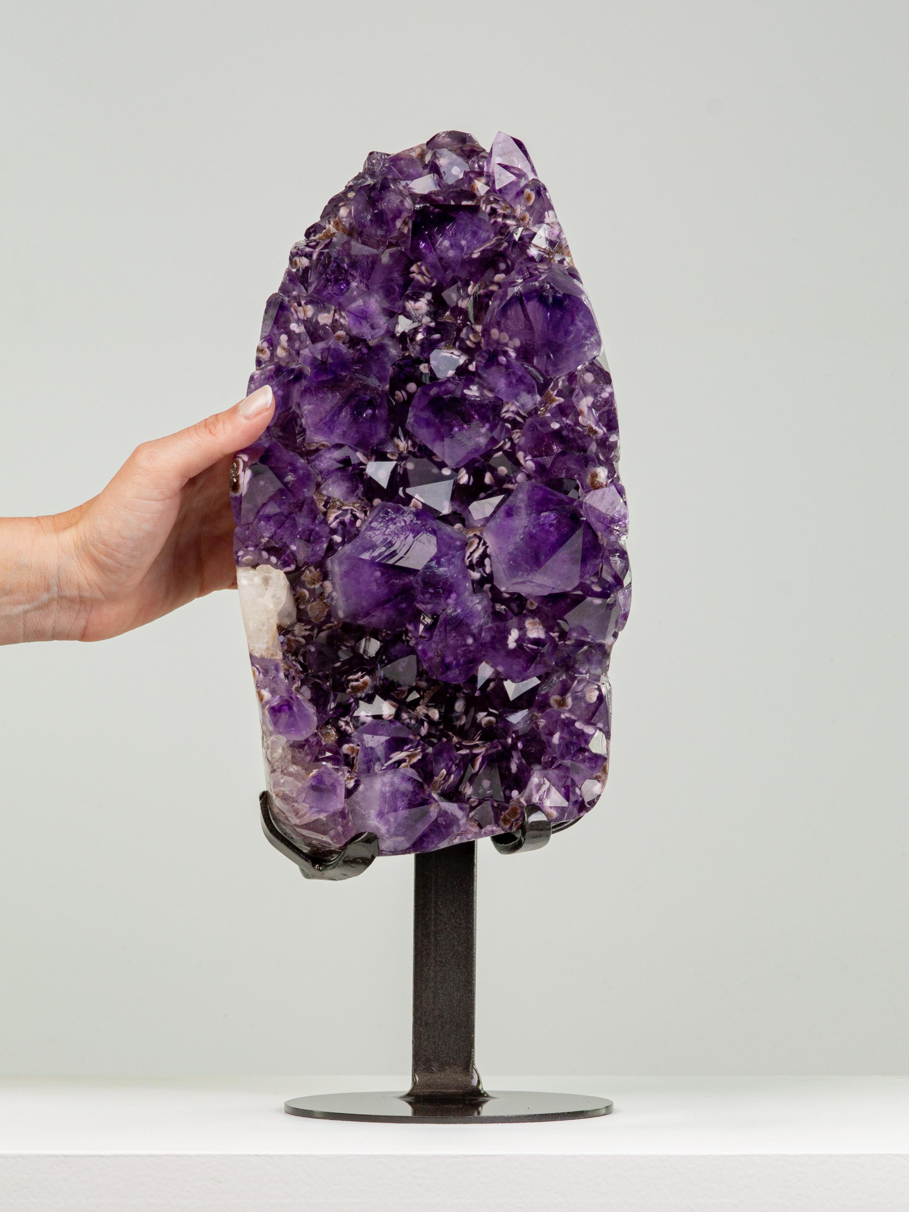An unusual piece of high quality deep purple amethyst with large peaked
crystals. Inside the amethyst multiple goethite crystals resembling rosettes
can be seen. Several of the crystals are overcoated in brown druze.

This piece was legally and