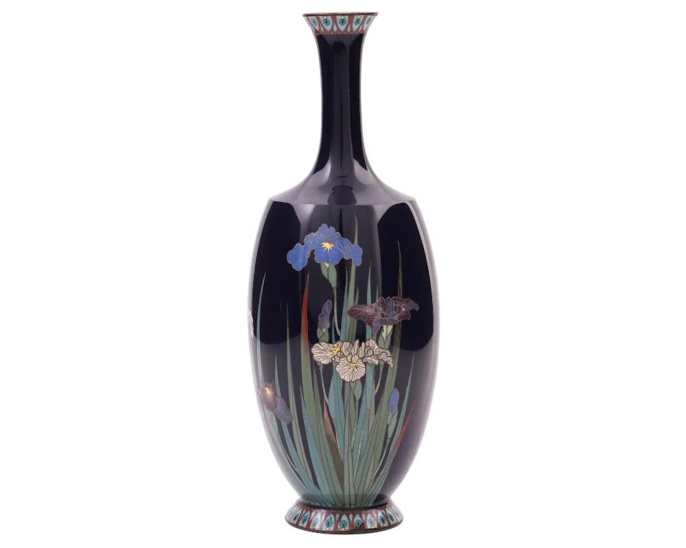 An antique Japanese, late Meiji period, enamel over gilt copper vase. with silver wire

The unusual shaped vase has a long fluted neck. The ware is enameled with a polychrome image of blossoming Iris flowers on the dark blue ground made in the