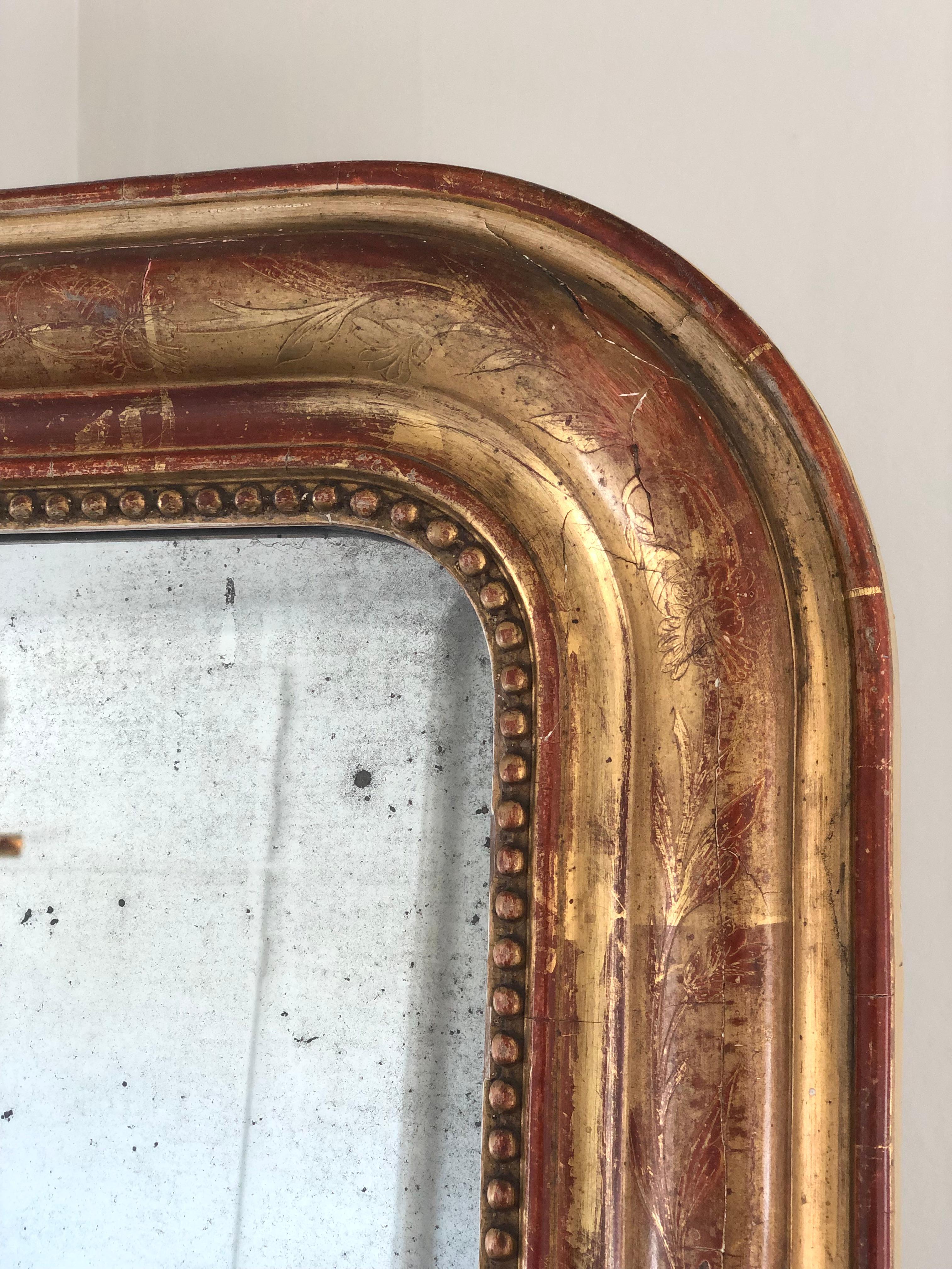 A very high-quality antique Louis Philippe mirror from France, late 19th century. An appearance with grandeur. The richly carved giltwood frame with a pearl rim and curved top corners has a beautiful worn gold leaf patina. Original mercury glass and