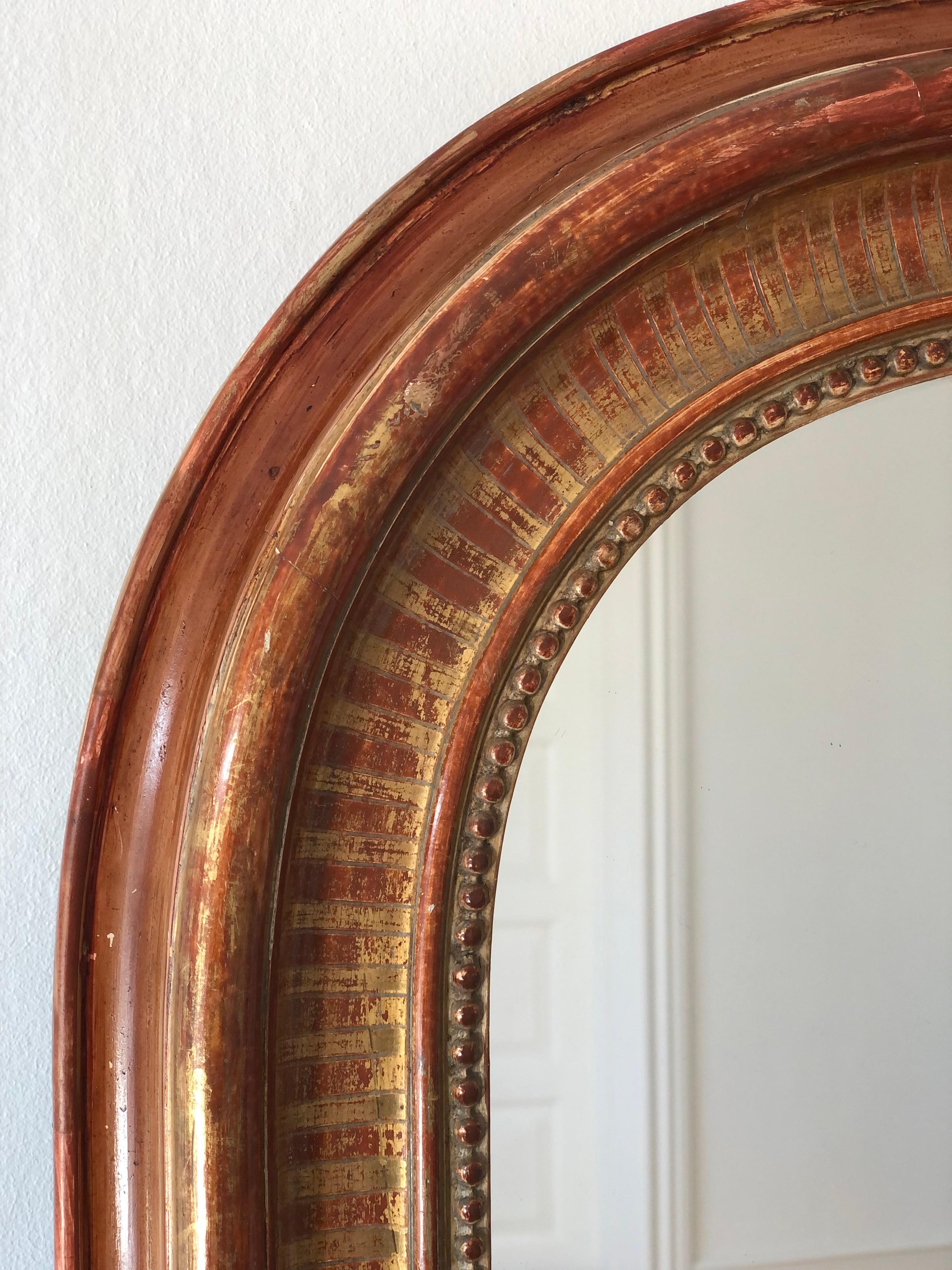 A very high-quality antique Louis Philippe mirror from France, dating to the late 19th century.
With an appearance of grandeur, the carved giltwood frame features gracefully curved top corners, a beautiful worn red leaf patina, and a delicate pearl