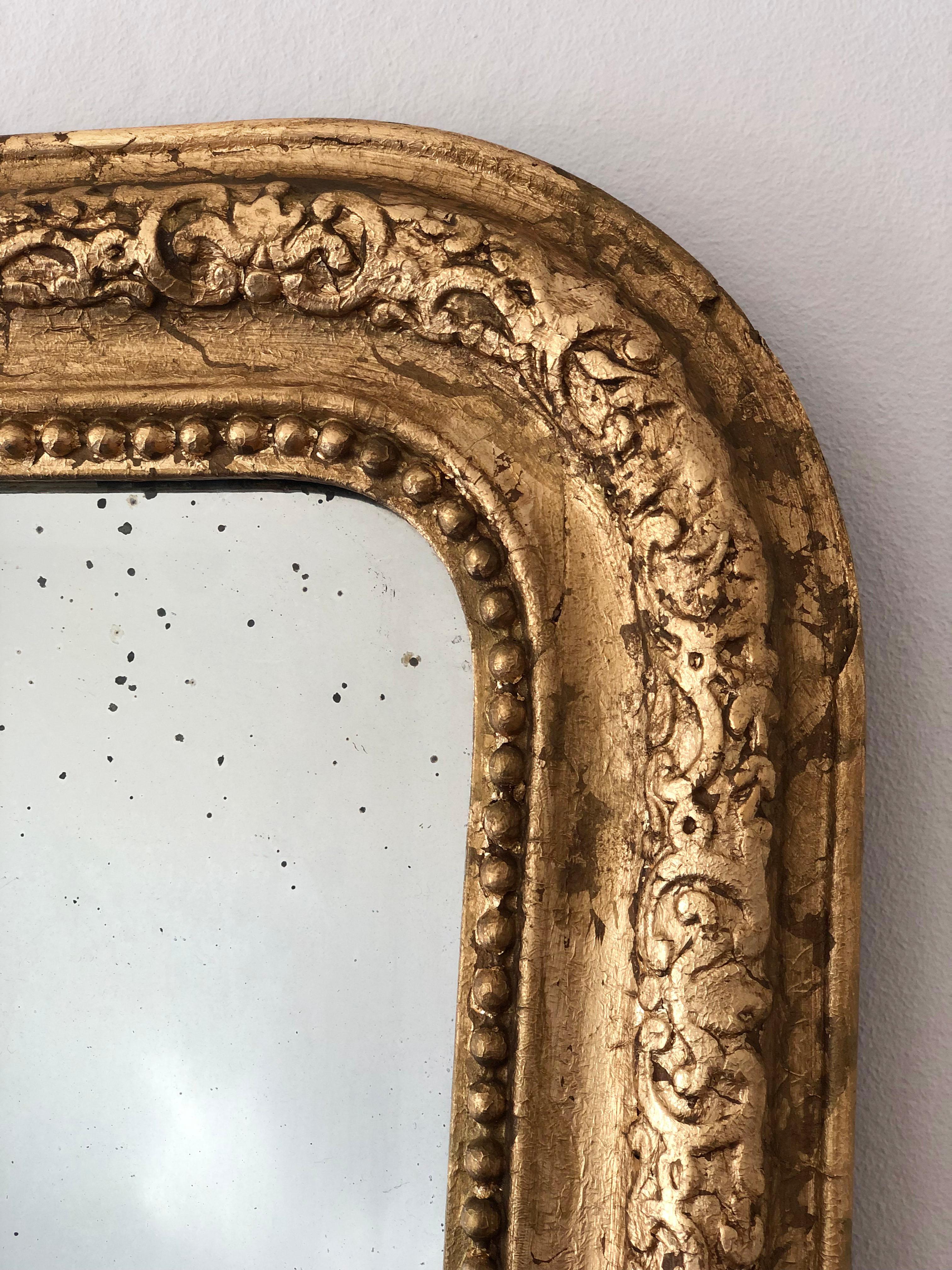 A very high-quality antique Louis Philippe mirror from France, dating to the late 19th century.
With an appearance of grandeur, the richly carved giltwood frame features gracefully curved top corners, a beautiful worn gold leaf patina, and a