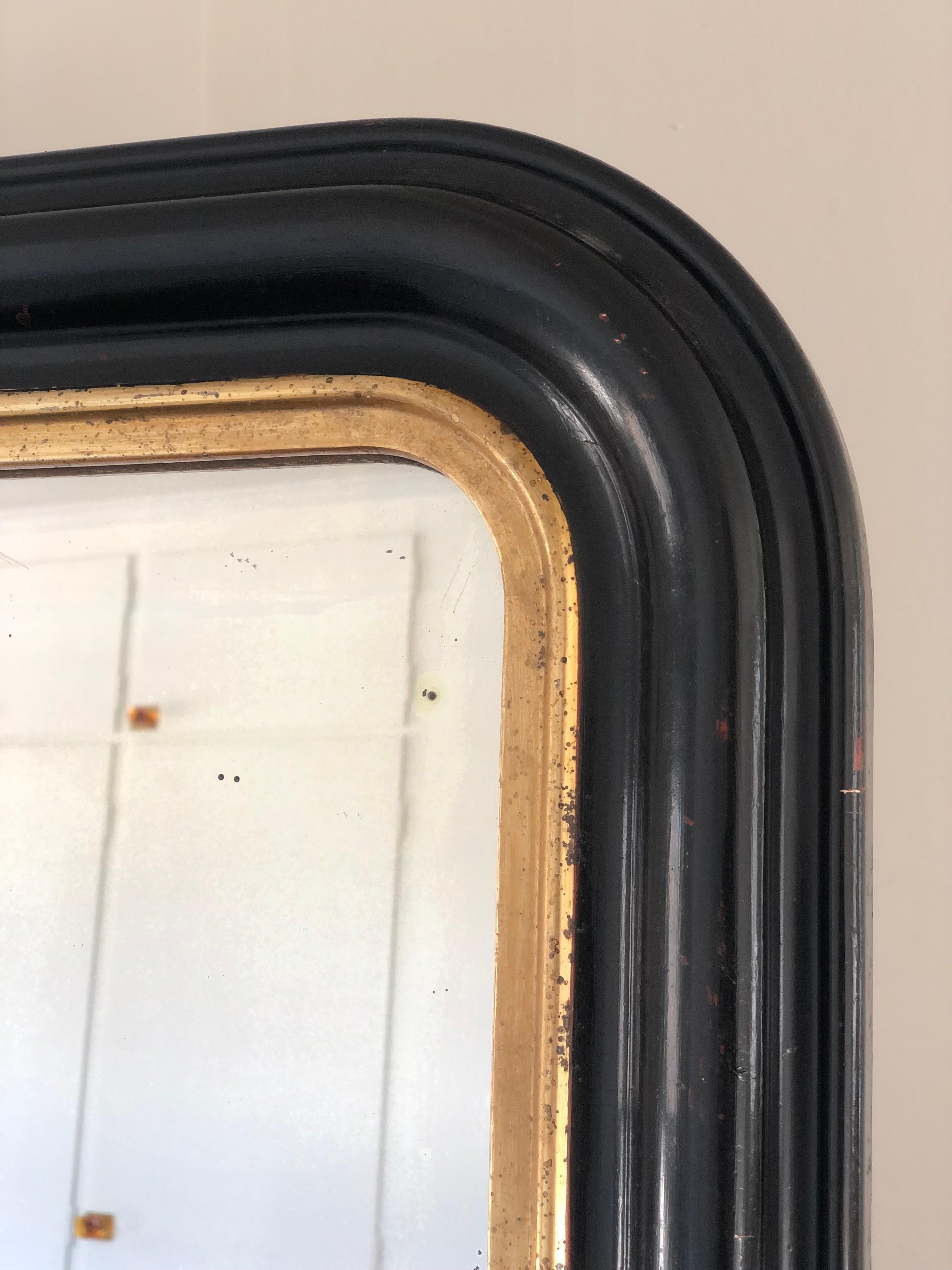 Miroir ancien Louis Philippe de très grande qualité, datant de la fin du 19e siècle et provenant de France. Une apparition avec grandeur. Le cadre richement sculpté avec des coins supérieurs incurvés en noir a un bord en bois doré. Verre de mercure
