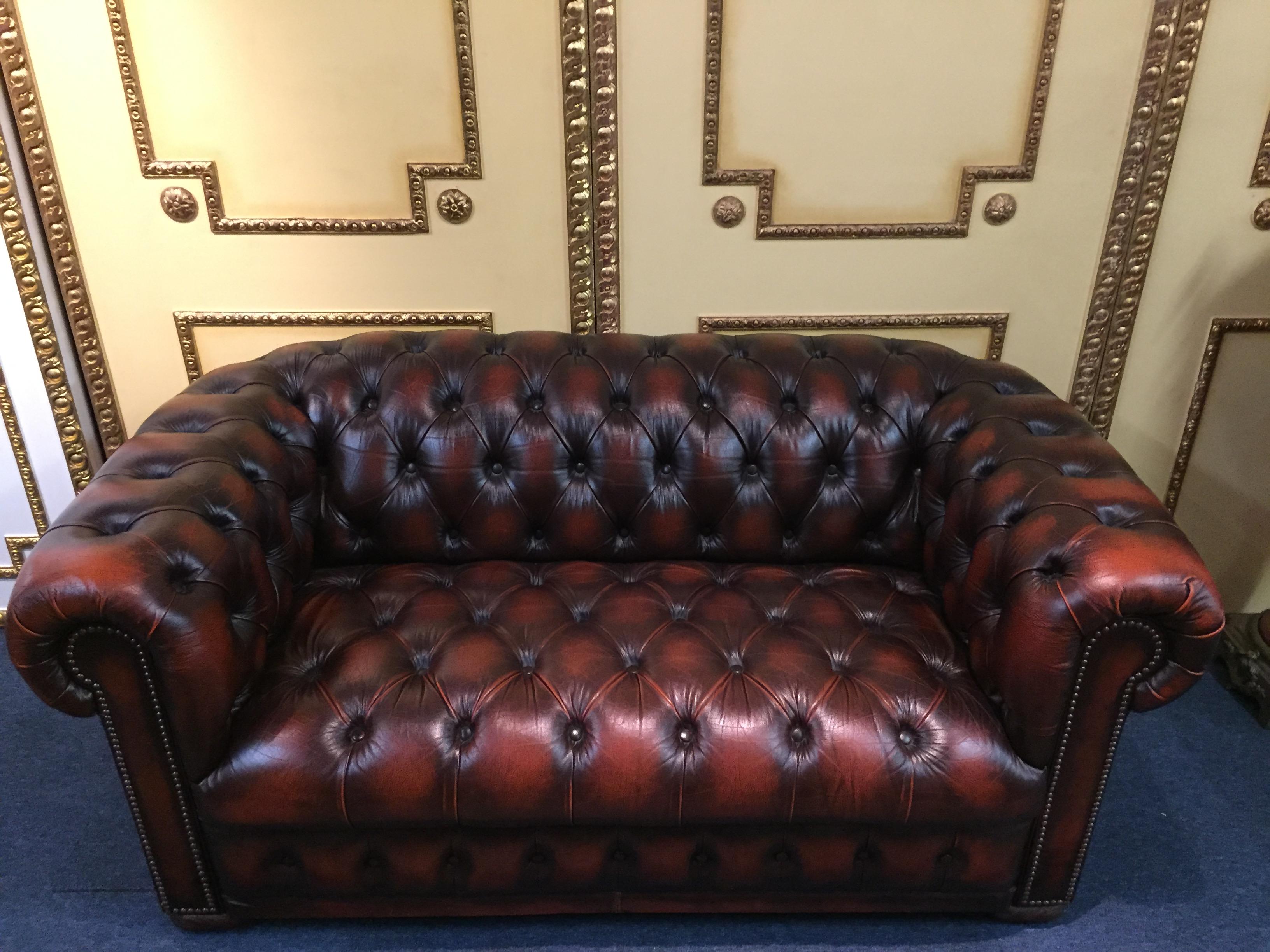 Classic chesterfield two-seat sofa England import.
Ideal for the office or the stylishly furnished apartment. The sofa is completely worked with real leather without any artificial leather and is built on a solid wood frame.
All seams are made by