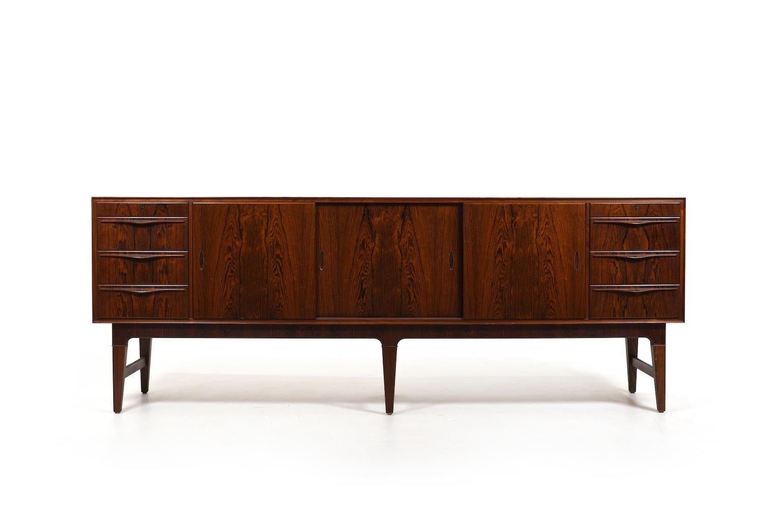 Bellissima credenza danese in legno scuro con maniglie intarsiate in ottone. Davanti con 3 ante scorrevoli e 8 cassetti. Dietro le porte con ripiani. Produzione di alta qualità. Danimarca anni '50.