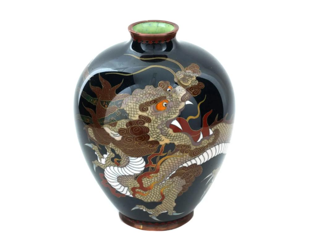 A high quality antique Japanese, late Meiji period, enamel over copper vase. The globular form vase with a short narrow neck. The ware is enameled with a polychrome image of a dragon against the black ground made in the Cloisonne technique. The neck