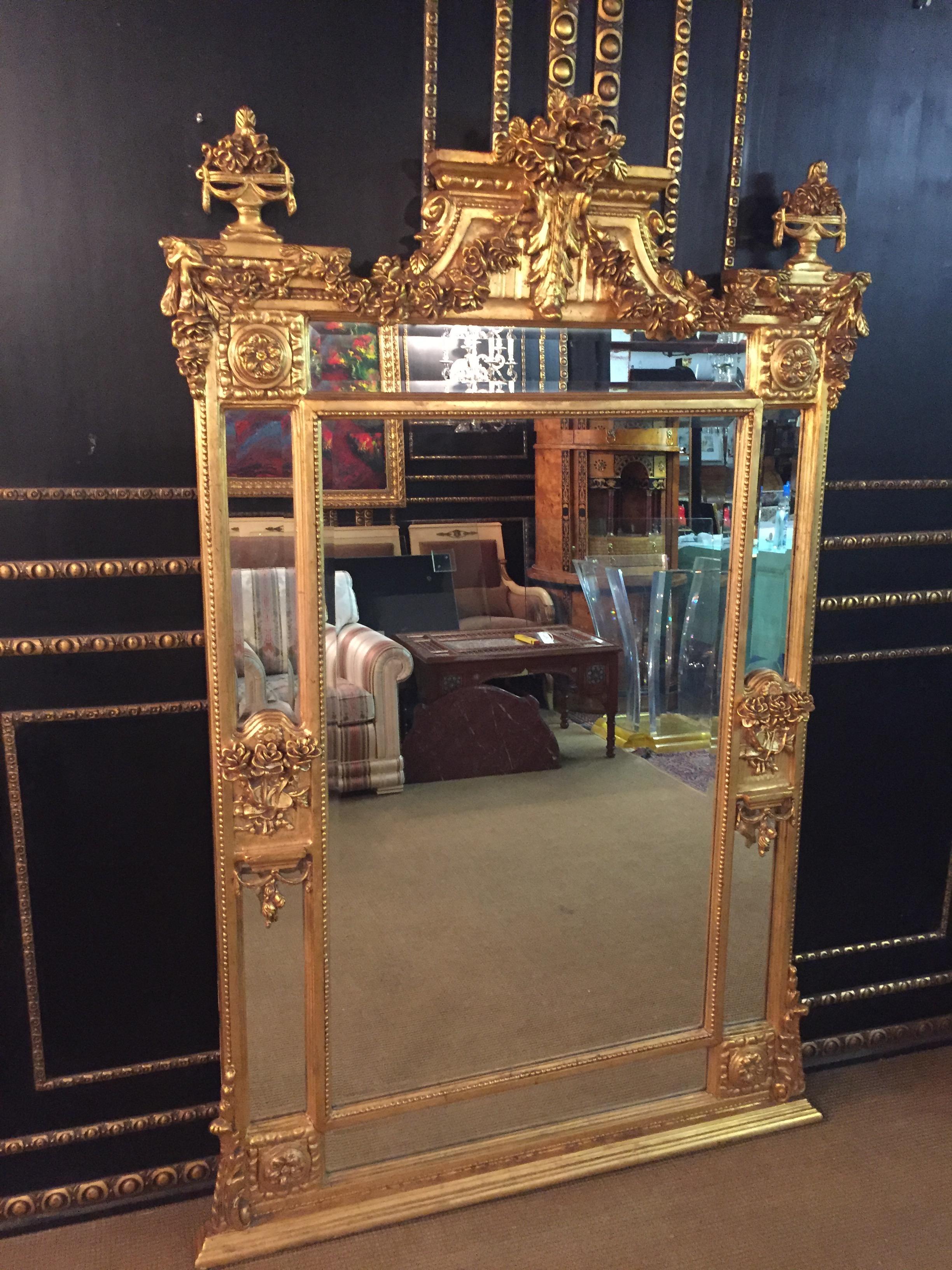 Wood and stucco gilt gilded. High-format, 3 cm faceted cut mirror glasses in profiled frame. The gable field is decorated with applied, sculpted classicist elements such as amphorae and garlands. Furthermore, the side framing, which are divided into