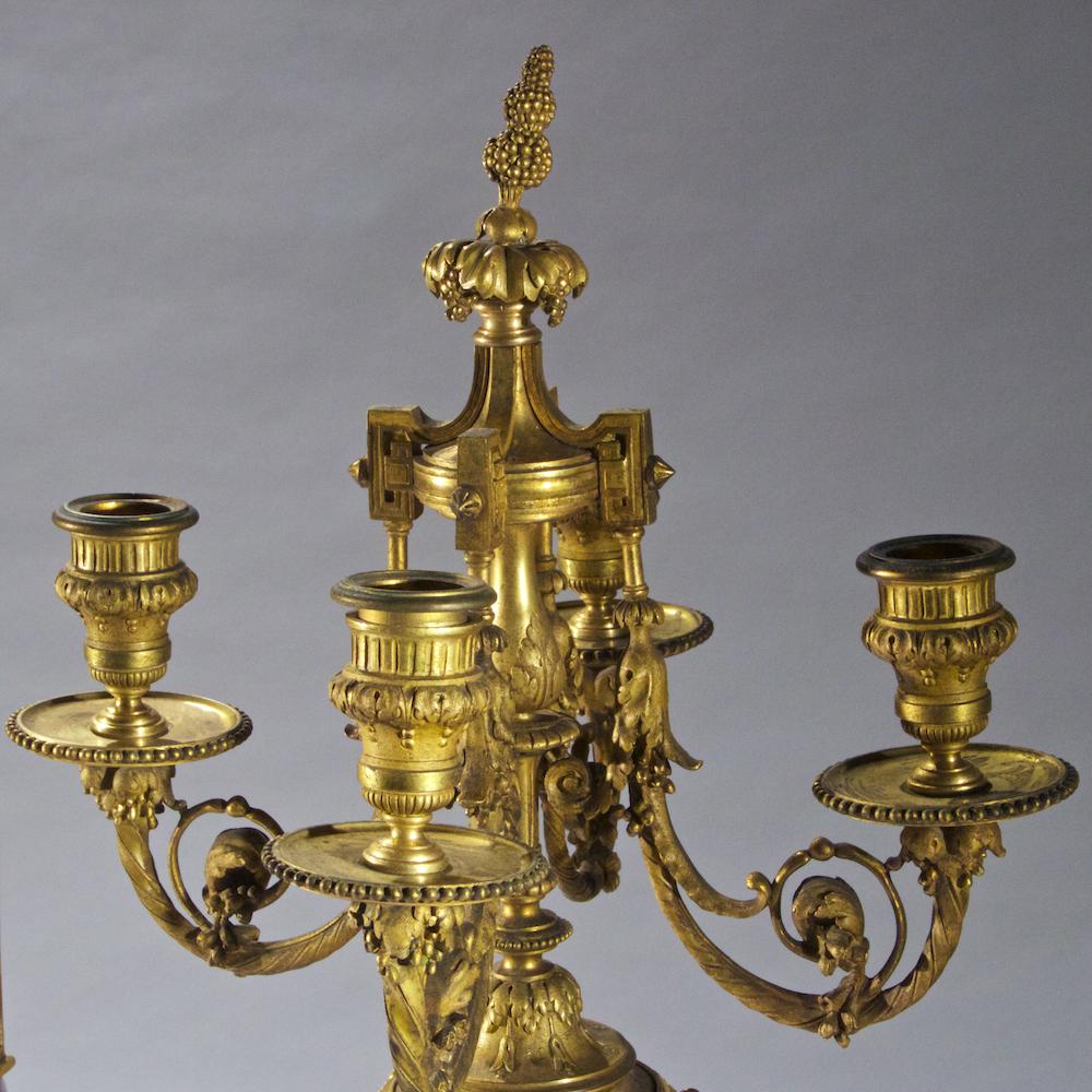 High Quality Sèvres-style Ormolu mounted porcelain and cobalt blue ground three piece garniture. The Sèvres-style centerpiece hand painted, jeweled, gilt-bronze mounted and cover. The Sèvres-style rare pair of four-branch gilt bronze jeweled cobalt
