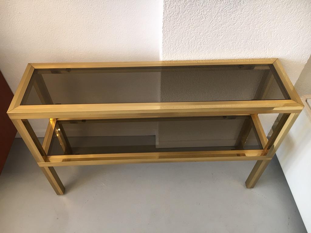 Solid brass and smoked thick glass two-tier console table, circa 1970s
High quality, very heavy, elegant glides
Very good condition.