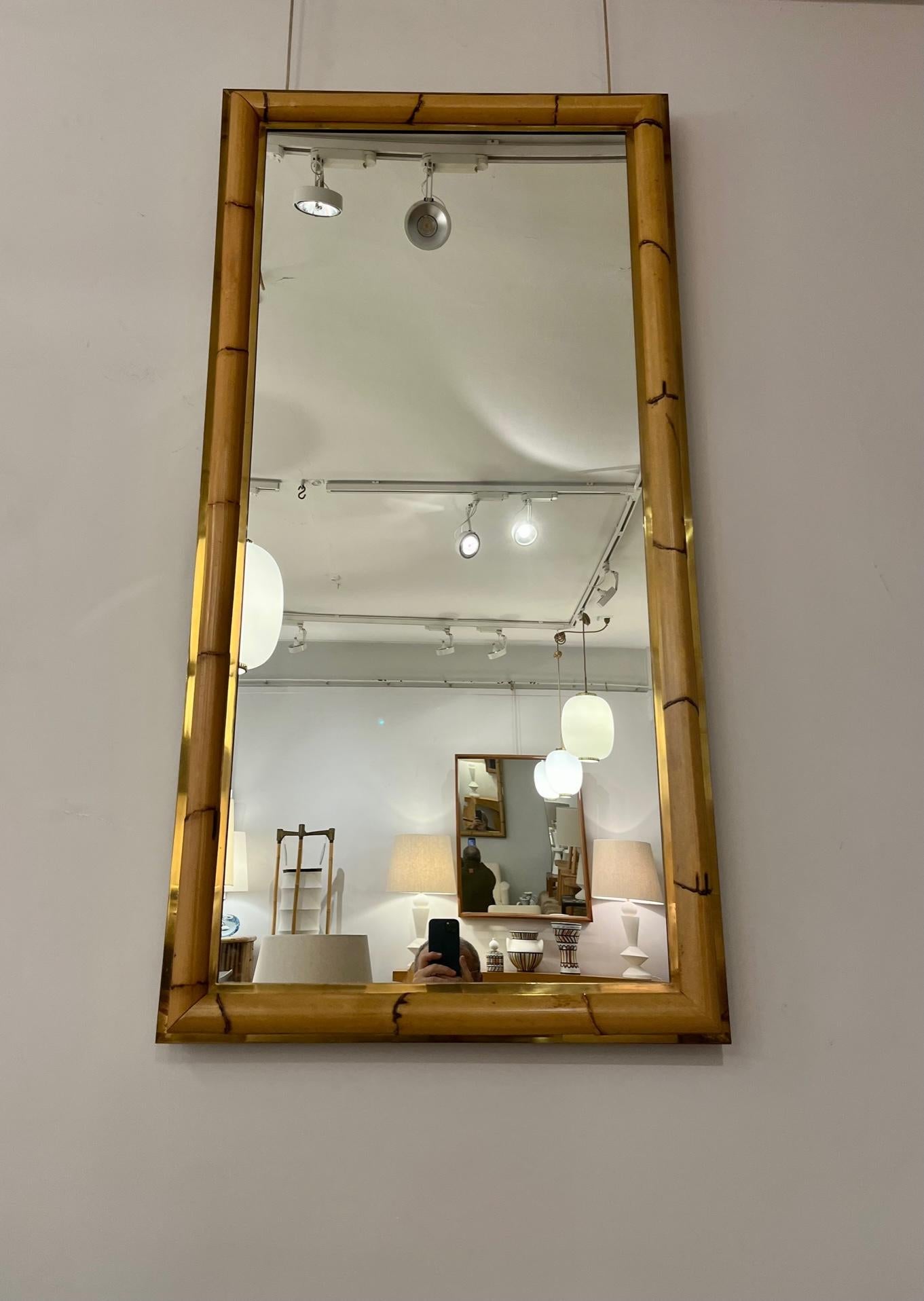 A high rattan and brass framed wall mirror. 
The frame consists of a thick rattan section, lined on both sides by a brass frame.
This mirror is ideally suited for a wardrobe or an entrance. 
Excellent vintage condition. 
Italy, circa