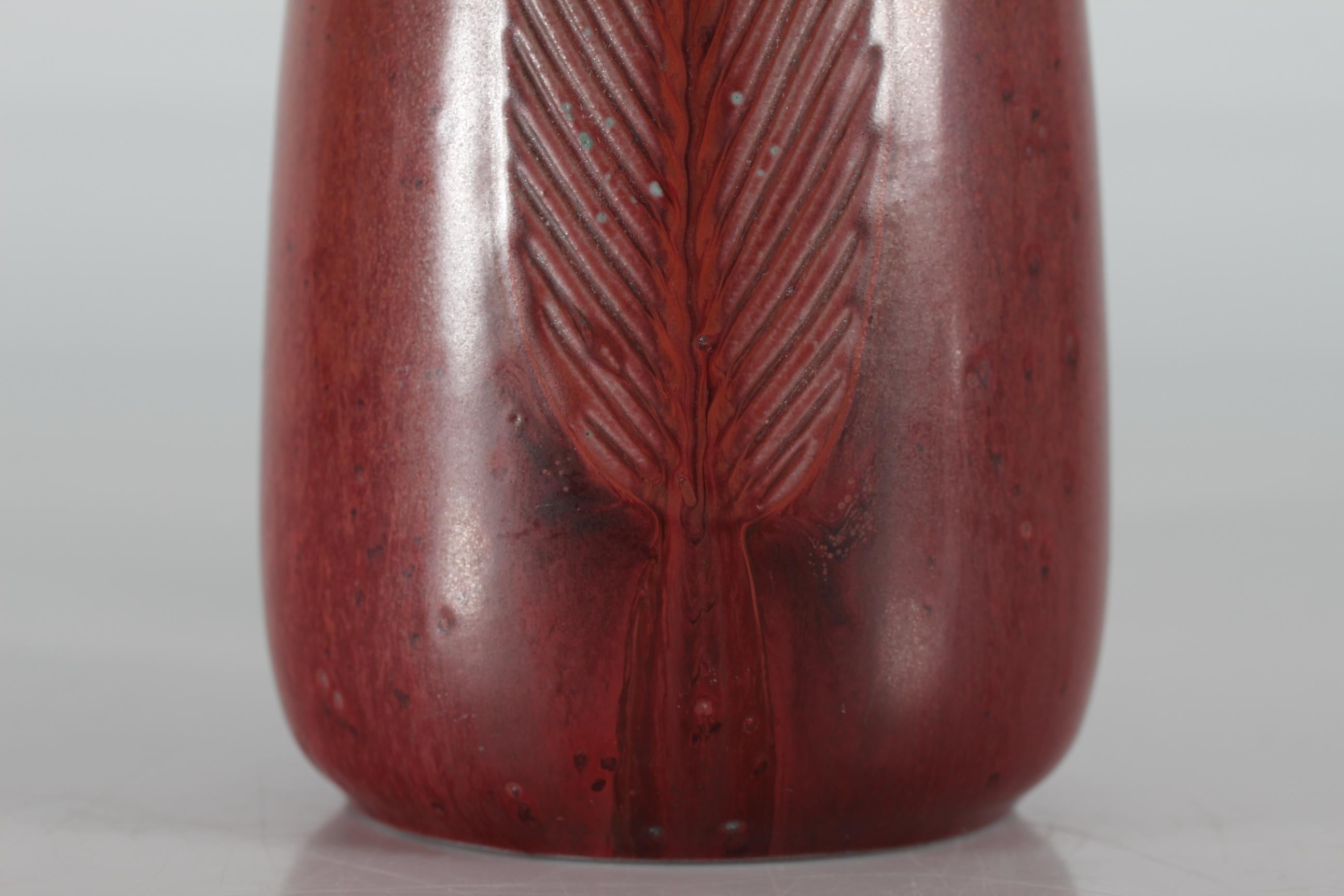 High and slim stoneware table lamp model no. 22140 designed by Danish ceramist Gerd Bøgelund (1923-1987) and manufactured by Royal Copenhagen.

The lamp foot has an incised ear of corn or leaf and is decorated with ox blood glaze.

Included is a