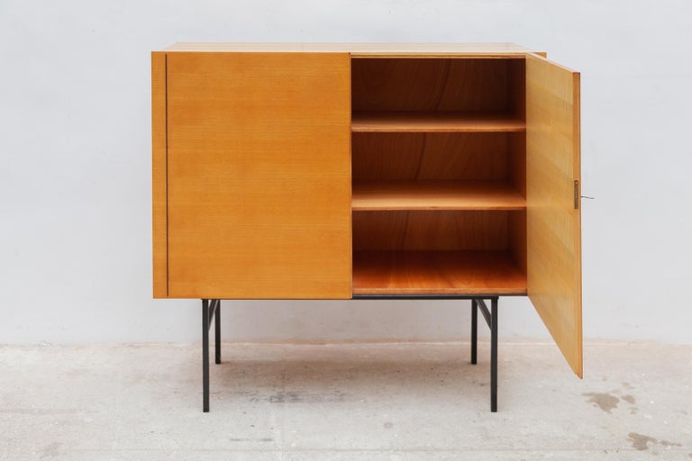 Modernist shaped high sideboard designed by Behr, Germany 1960s. This sideboard was made of teak wood and has a black lacquered metal base. Shelves behind the double folding doors. Labeled with Deutsche Werkstätte, Behr at the back side of the