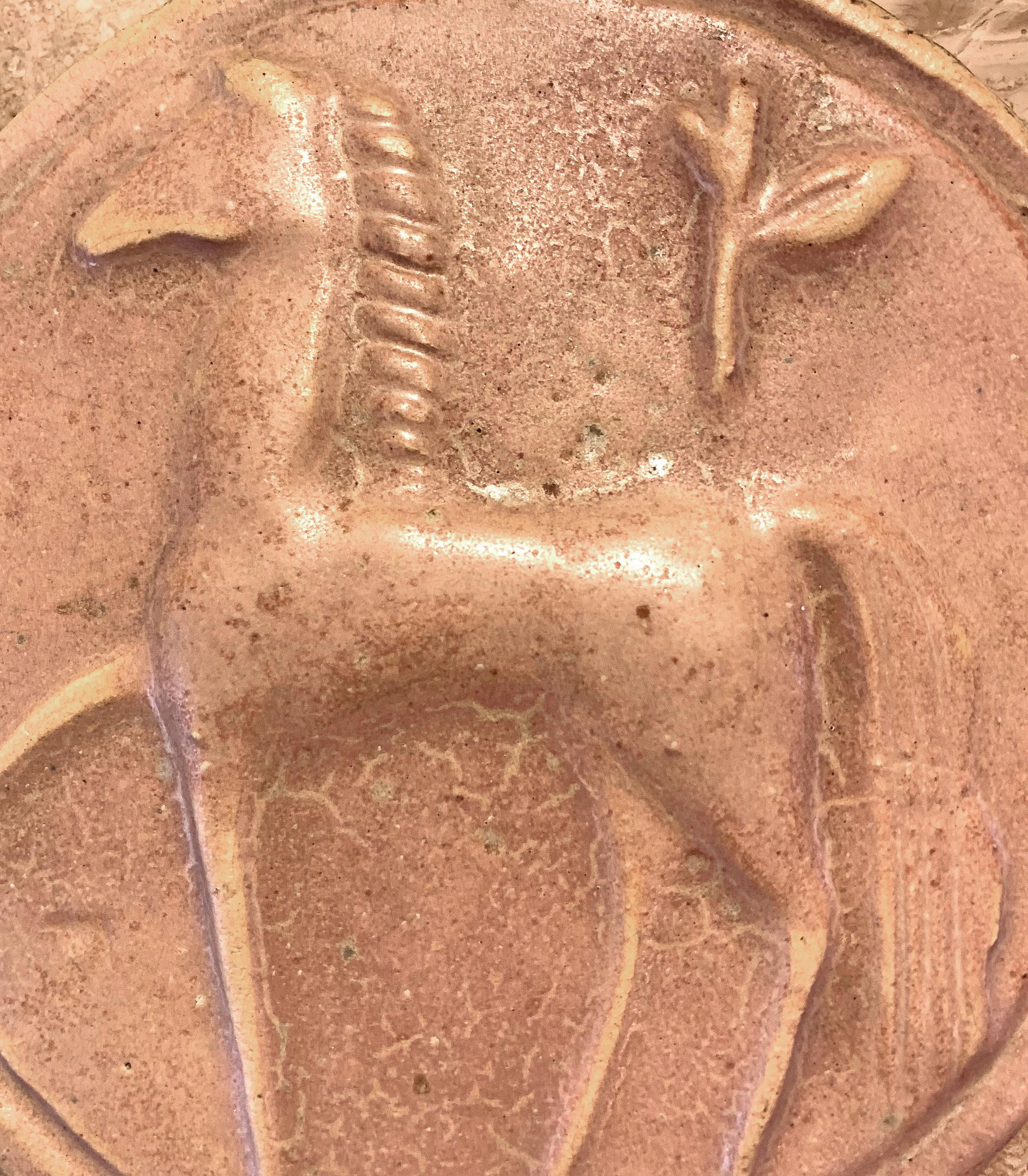 Demonstrating a modern take on Etruscan and other ancient sculpture, this 1941-vintage relief rondel depicts a high-stepping horse and a leafing branch, all bathed in a clotted, dusty-rose glaze that is lovely. The piece is signed 