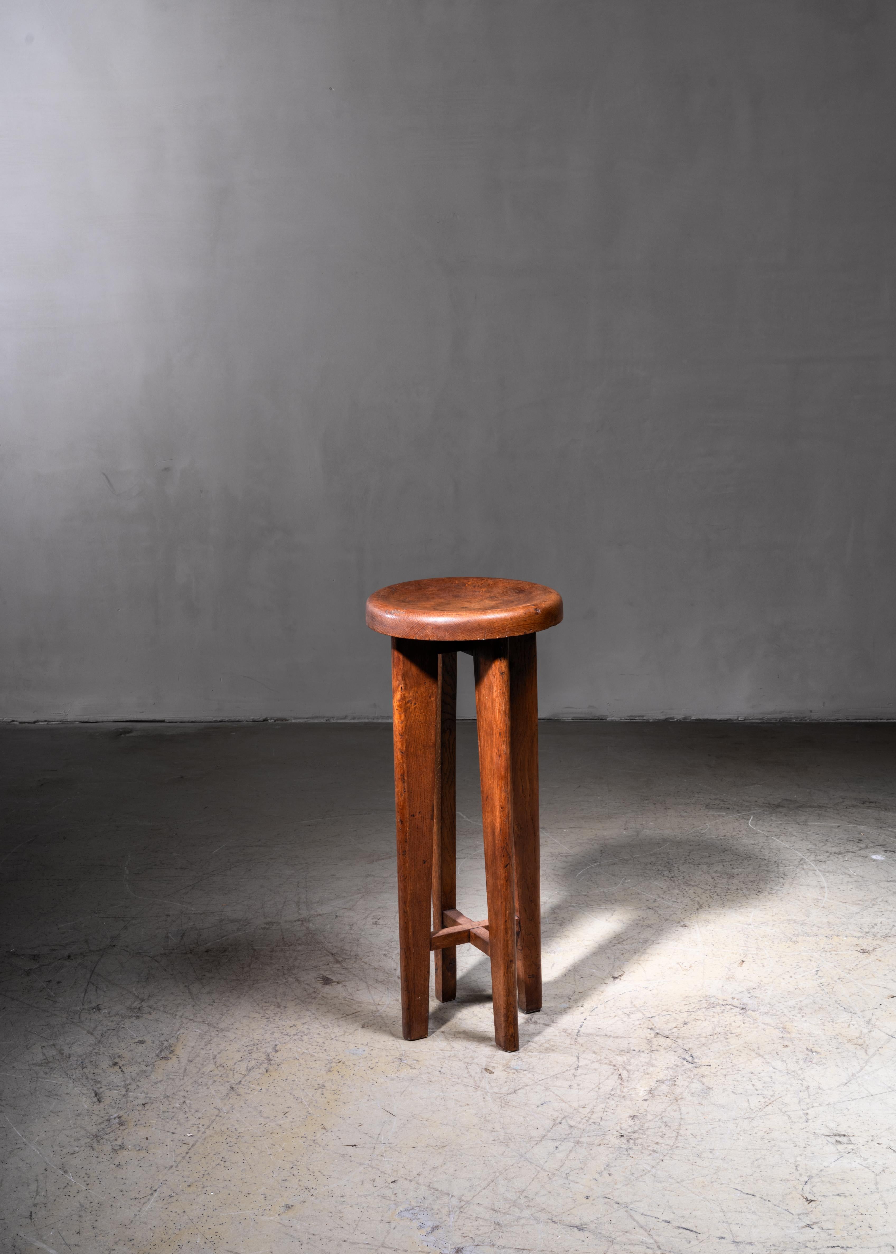 A high French stool in solid oak. It has architectural legs and a wonderful inward curved seat. A beautiful piece with a stunning patina. The stool is reminiscent of the work of Charlotte Perriand and Pierre Jeanneret.