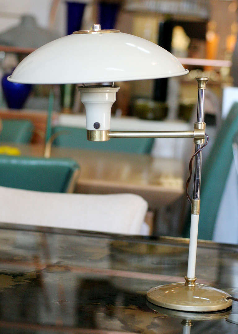 Hochwertige Schreibtischlampe aus der Mitte des Jahrhunderts mit einem Korpus aus emailliertem, mattweißem Stahl und Messingakzenten. Die Leuchte hat einen verstellbaren Arm und einen einzigartigen Stahlschirm.