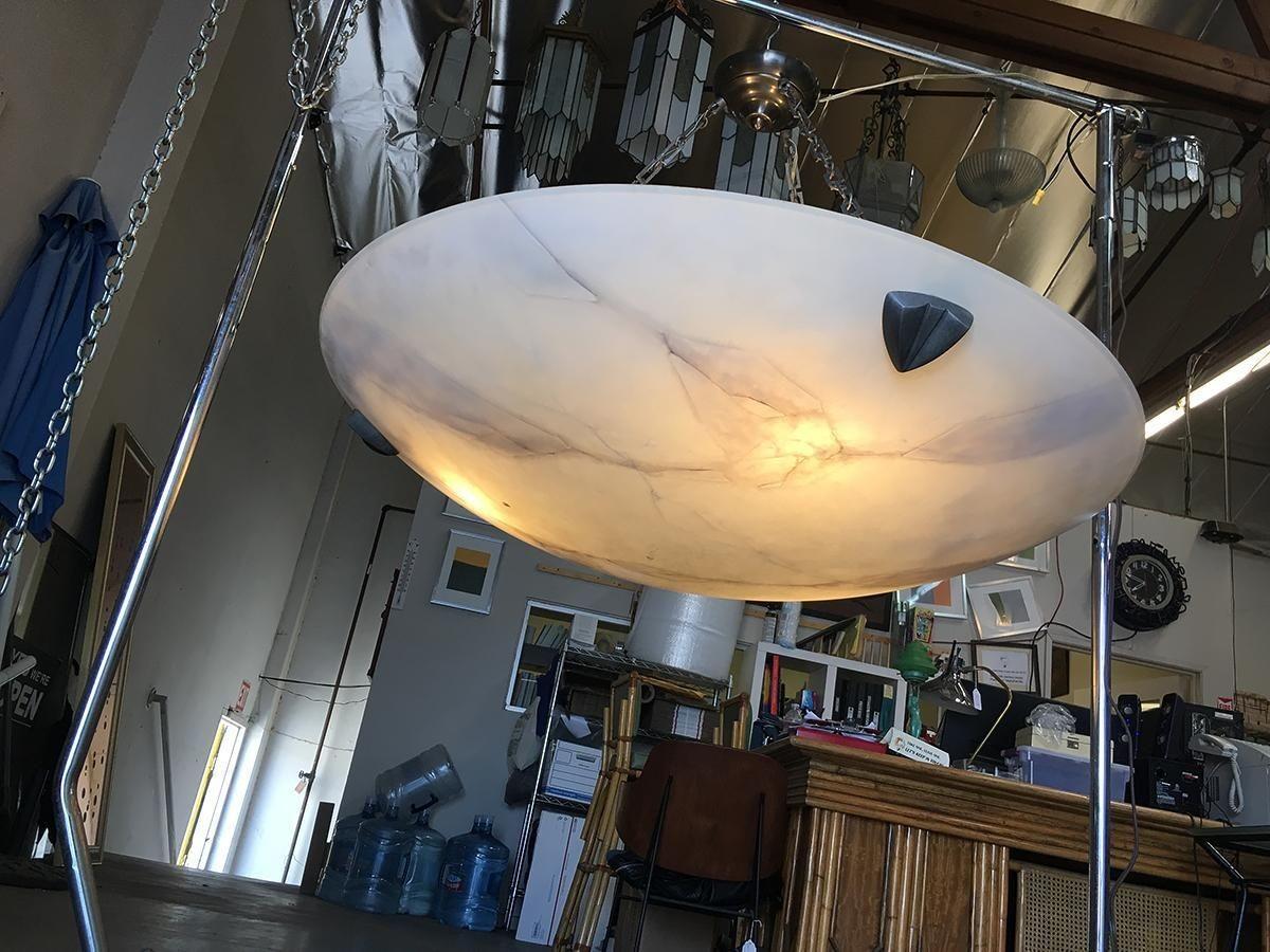 This Style of Modern Faux Alabaster Saucer chandelier is a contemporary lighting fixture designed to add sophistication and elegance to a space. It features a large carved saucer made from faux alabaster, a material known for its resemblance to real
