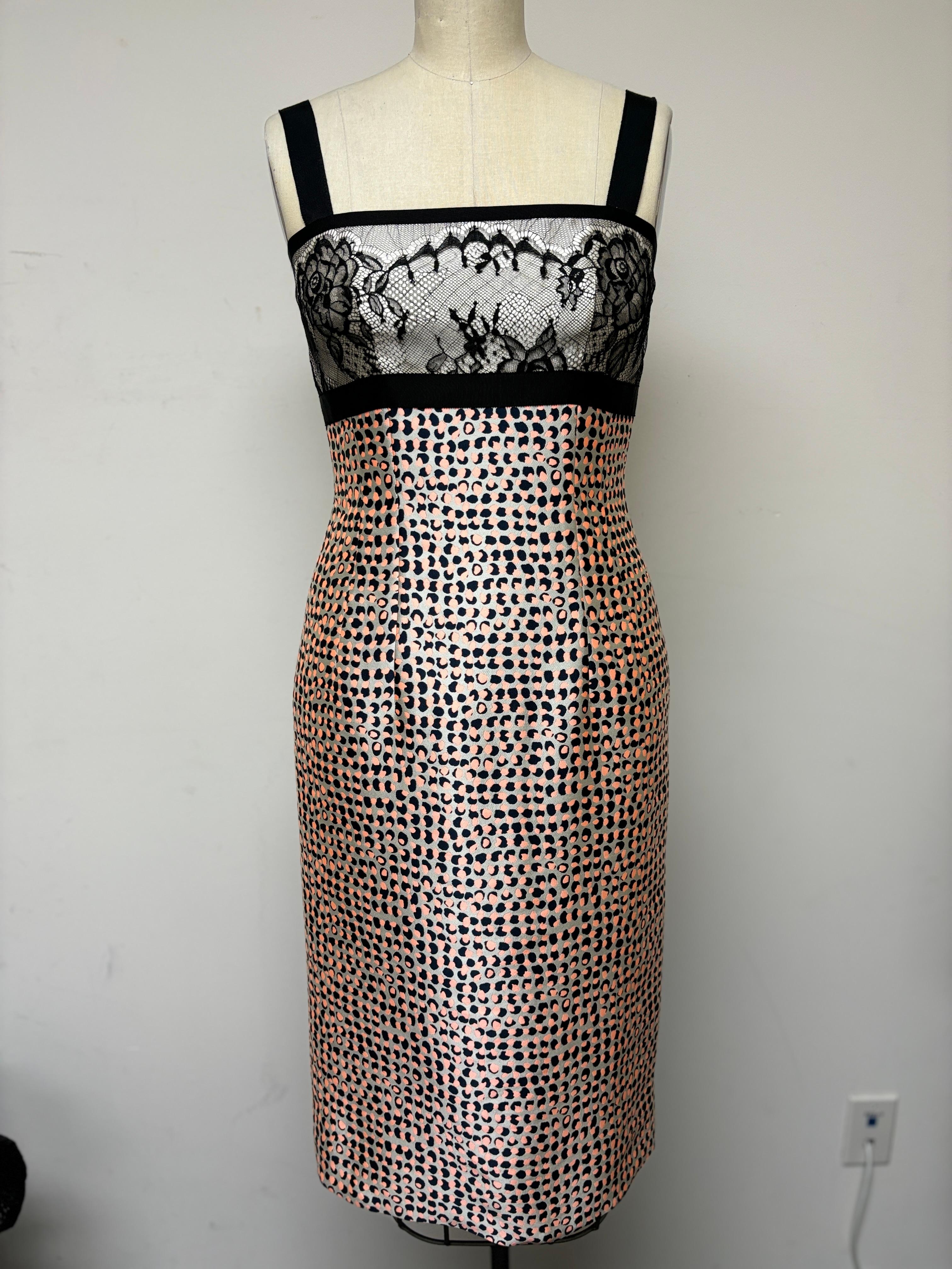 Un encantador vestido de lunares combinado con encaje negro y estampado de lunares de fantasía Taroni en negro, coral y blanco. Un divertido vestido lleno de encanto definido por tirantes de grosgrain negro, que le dan un refinamiento y un ajuste