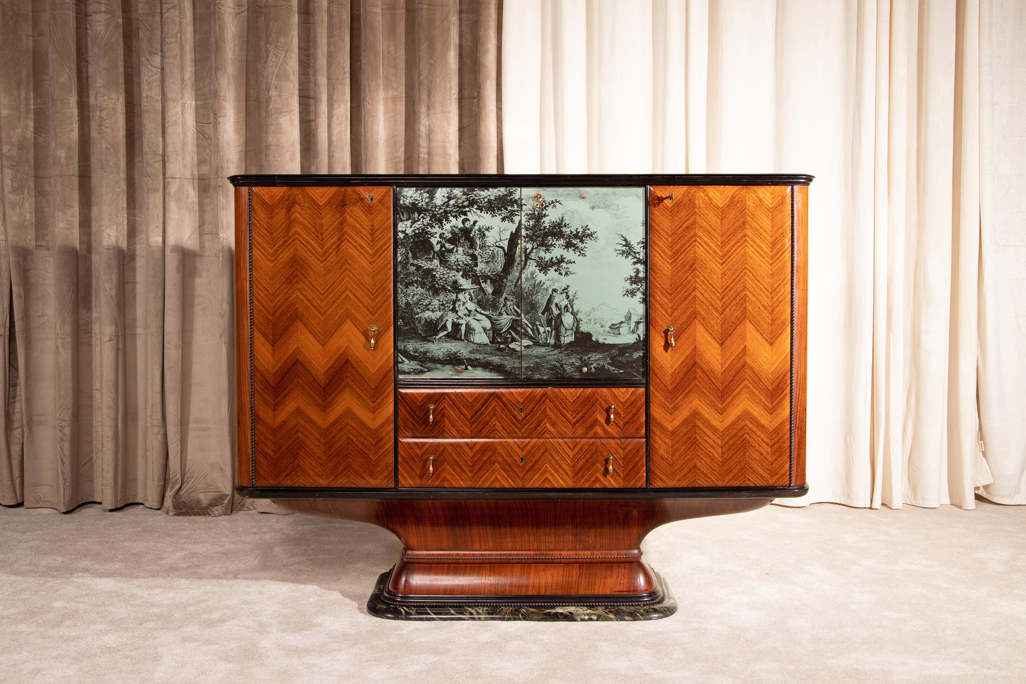 Raffinato mobile bar di produzione italiana, anni 40.
Realizzato nello stile di Osvaldo Borsani e Vittorio Dassi, questo capolavoro rappresenta al meglio la qualità dell'artigianalità italiana.
Sapientemente impiallacciato con un effetto spinato,