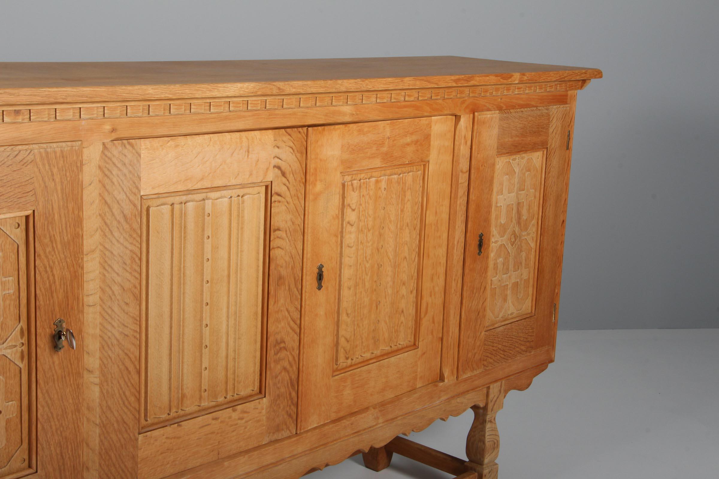 Striking highboard in oak with rich carved details. By Henry Kjærnulf. 

Refreshing design with bold Baroque coming together nicely with Mid-Century Modernism.

Made by EG møbler in the 1970s.
 