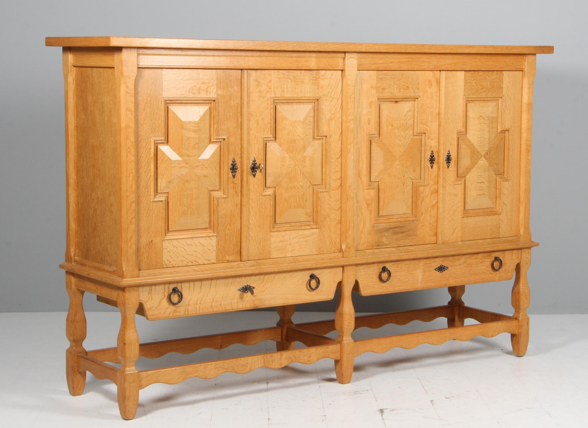 Striking highboard in oak with rich carved details. ByHenry Kjærnulf. 

Refreshing design with bold Baroque coming together nicely with Mid-Century Modernism.

Made by EG møbler in the 1970s.
 