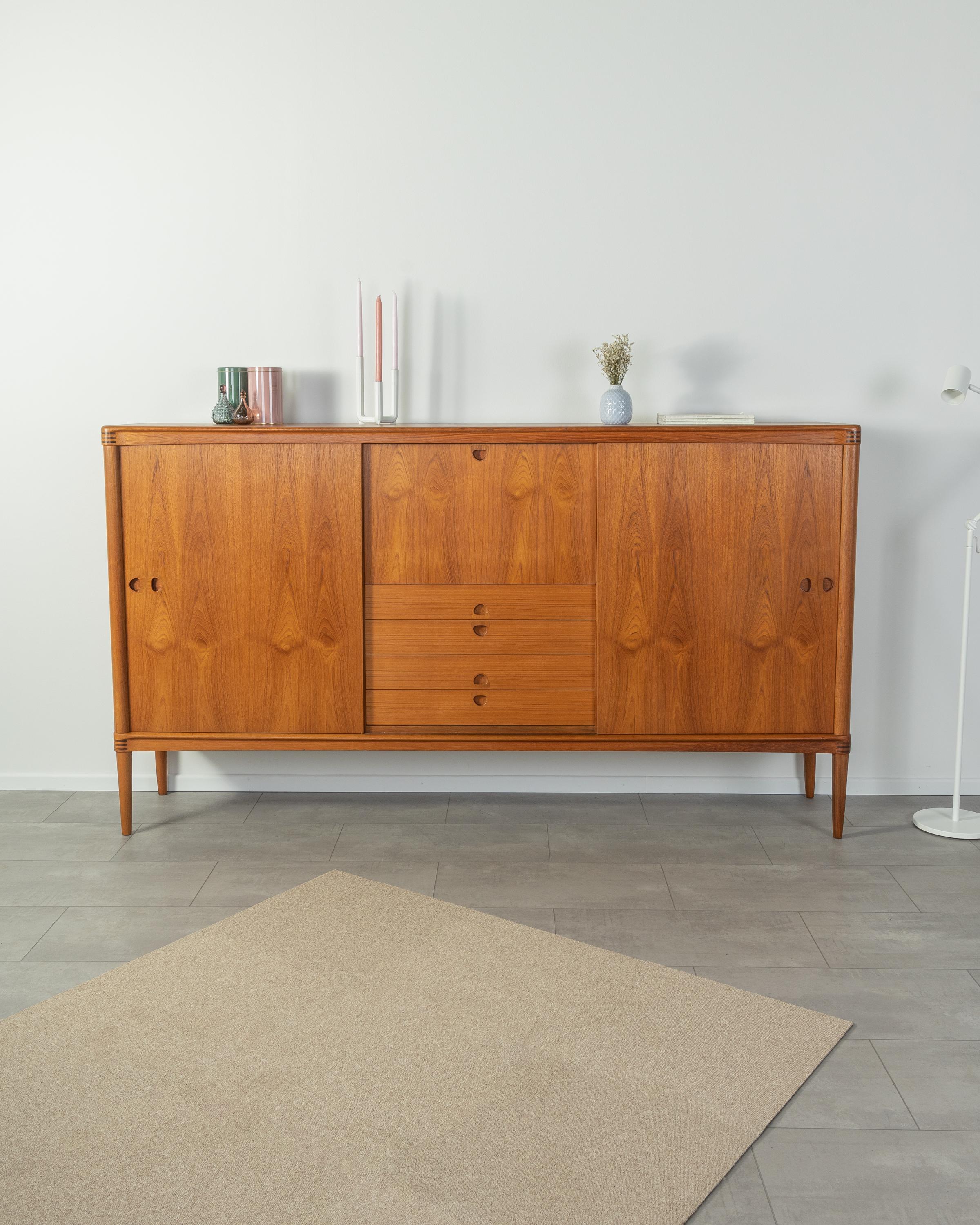 Classic highboard from the 1960s. High quality corpus in teak veneer with two sliding doors, four drawers, a hinged compartment, seven shelves and cigar shaped feet.
Quality Features:

 Accomplished design: perfect proportions and recognizable