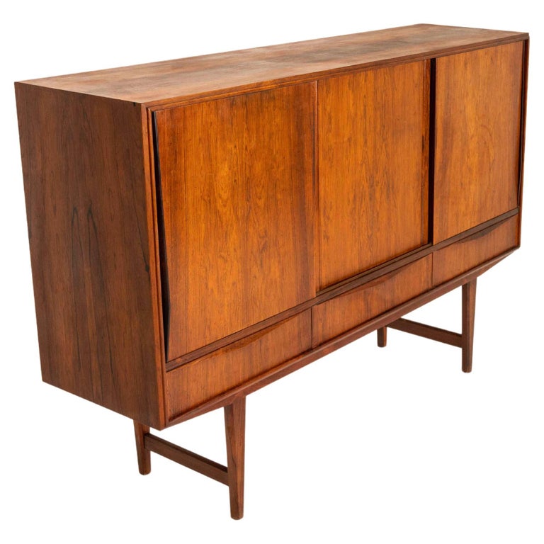 Nice highboard in rosewood for E.W. Bach from Denmark, ca the 1960s. This highboard has three sliding doors and three drawers. Behind the sliding doors are shelves and on the right side, there are two nicely designed drawers. The top rests on four