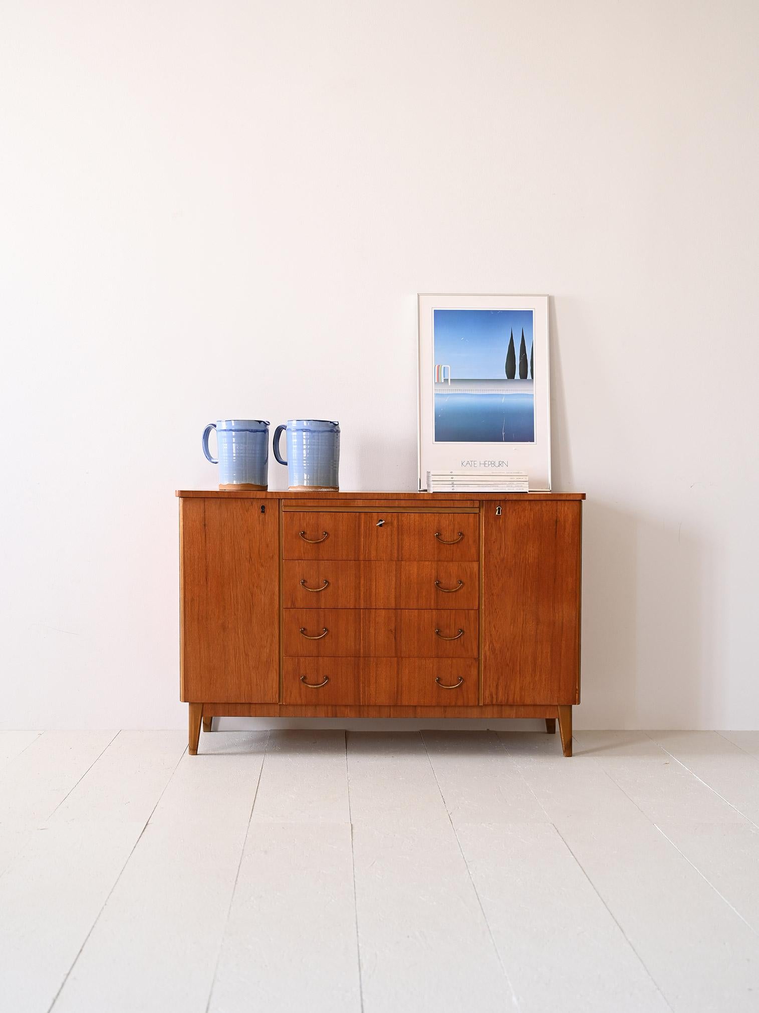 Scandinavian sideboard with central drawers.

This vintage-flavored piece of furniture is characterized by the gilded handles on the drawers and the division of space into three compartments. On either side is a storage compartment with a hinged