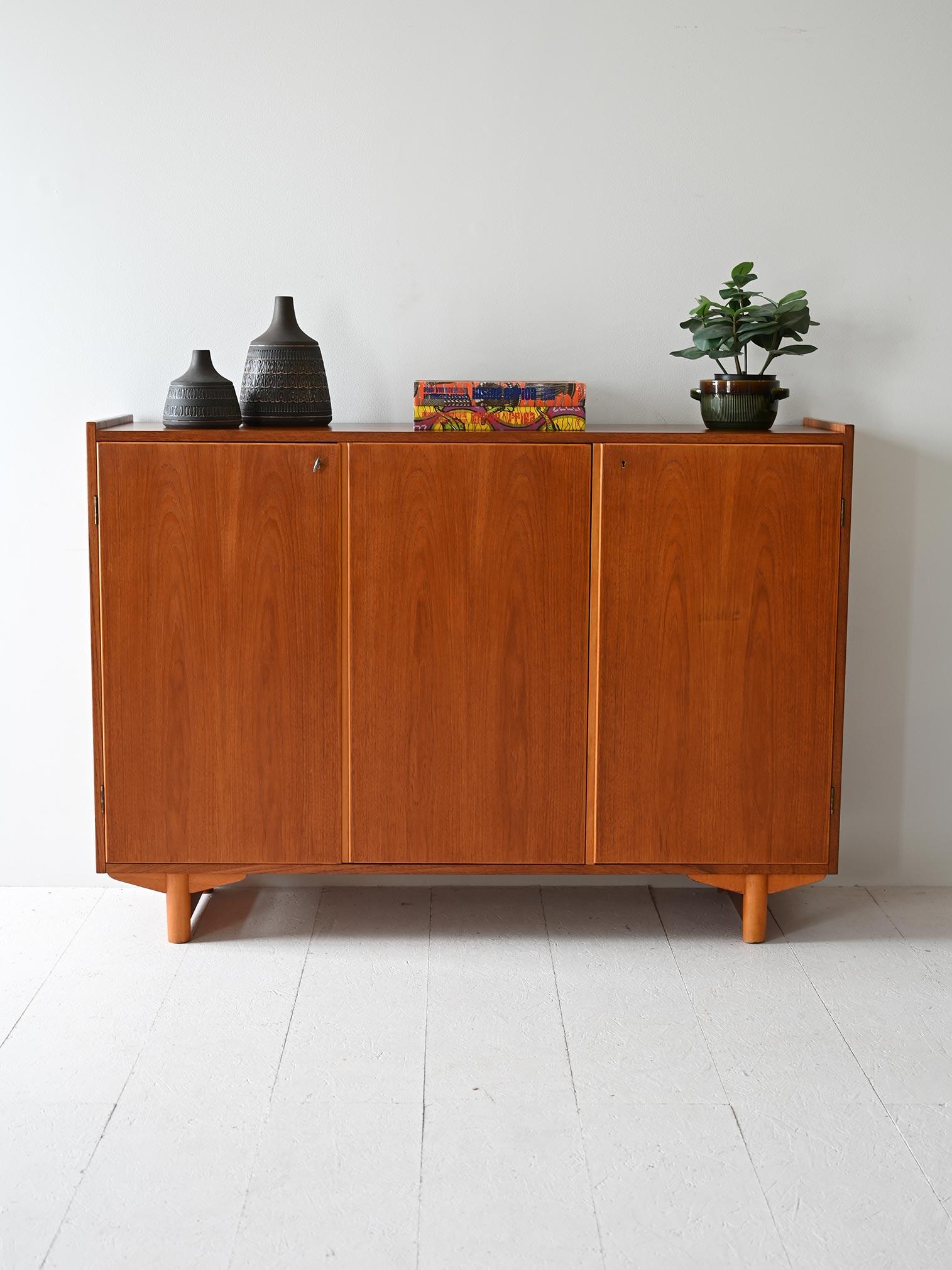 Scandinavian 1950s teakwood sideboard consisting of three lockable hinged doors. The interiors are divided by shelves.

This Scandinavian teak sideboard, made in the mid-century modern design period, has three hinged doors complete with locks. The