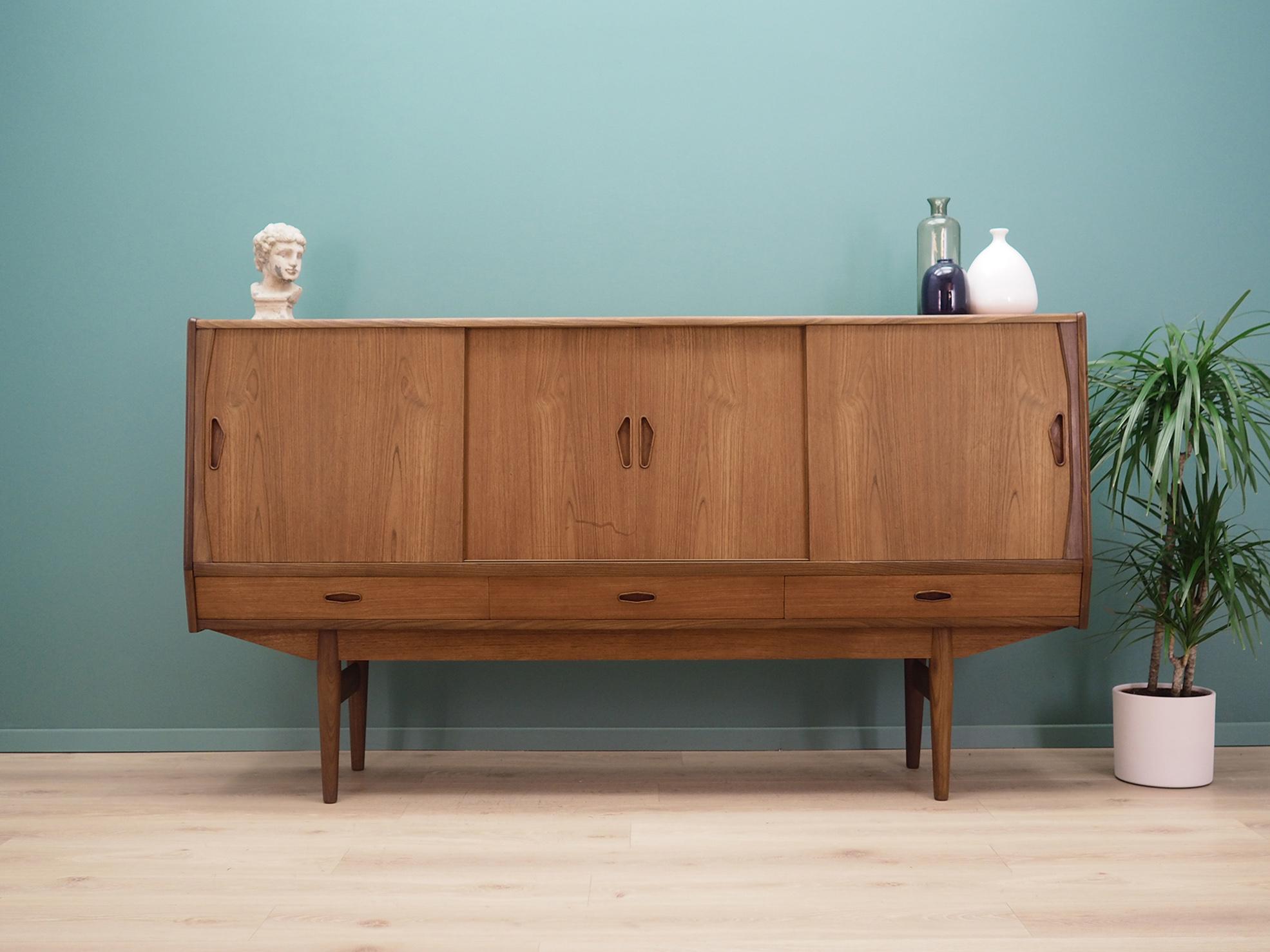 Highboard was made in the 1970s, Danish production.

The structure is covered with teak veneer. The legs and handles are made of solid teak. The surface after refreshing. Inside space has been filled with practical shelves with height adjustment.