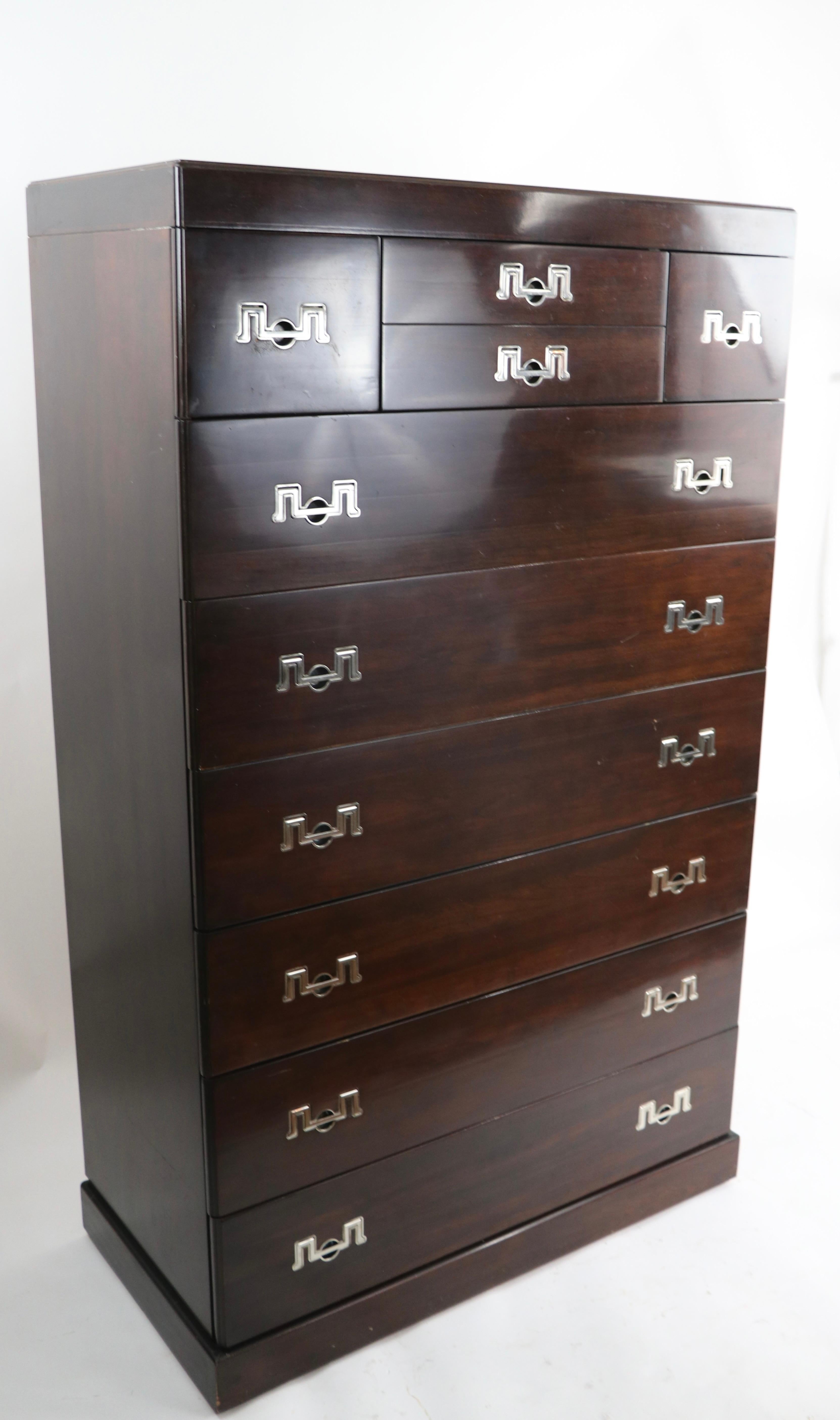 Exceptional and impressive 9 drawer highboy by Henredon, having a dark wood case ( mahogany or walnut we believe ) with stylized bright chrome bale handle pulls. The chest features three drawers across the top over (6) drawers. This example is in