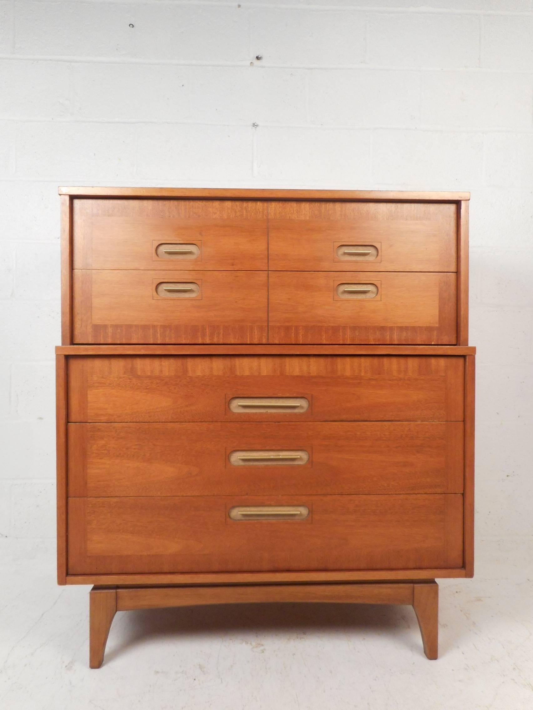 This gorgeous Mid-Century Modern highboy dresser features oval recessed pulls and splayed legs. A sleek case piece with five hefty drawers offering ample storage space. The stacked style straight line design and vintage walnut finish add to the