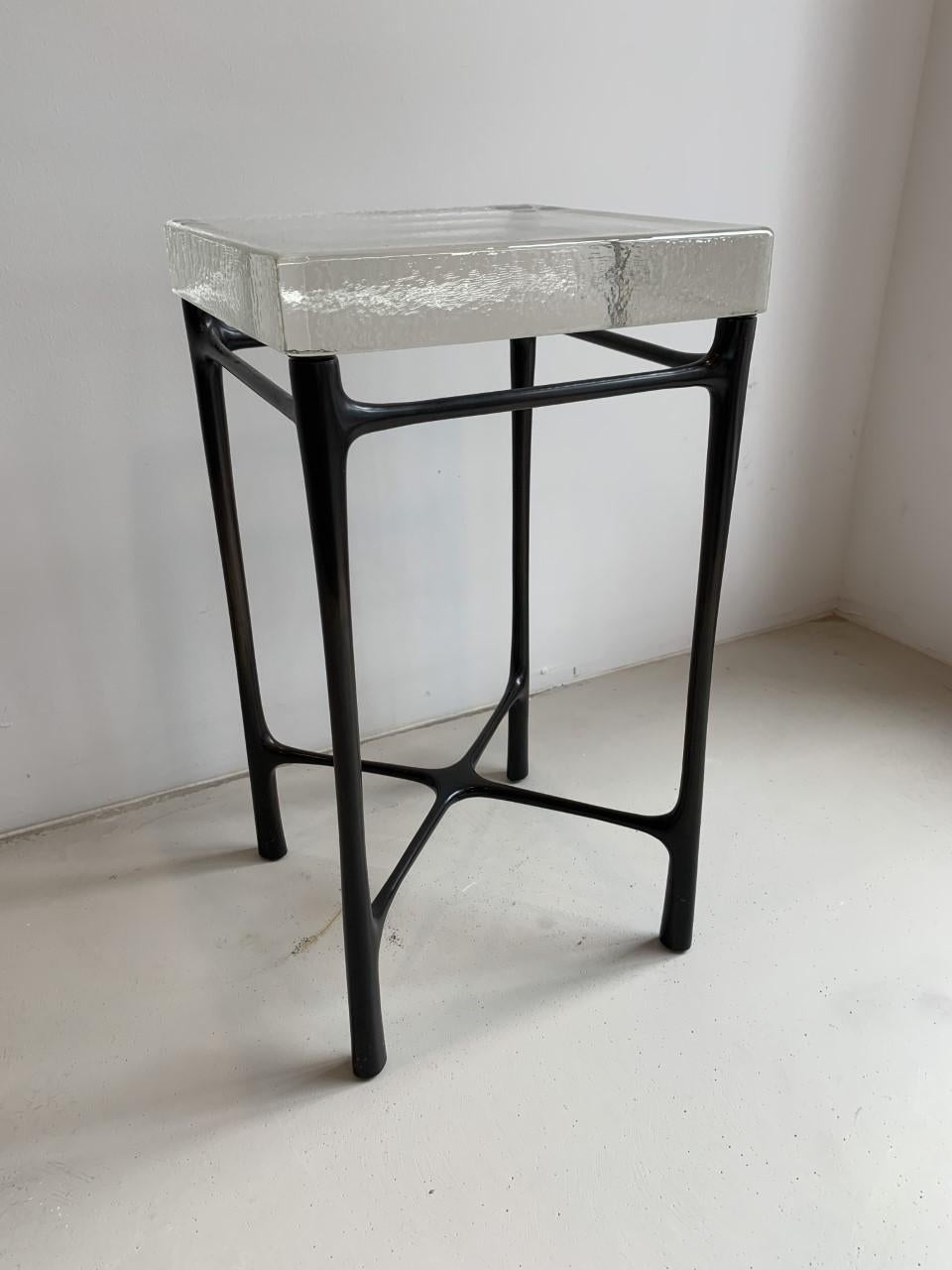 Dark Cast bronze base with clear cast glass top.