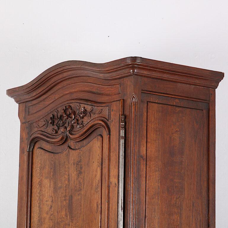 A French oak ‘bonnetiere’ or single door armoire with paneled oak sides and a shaped paneled door with carved details. Fitted with adjustable shelves. 

 