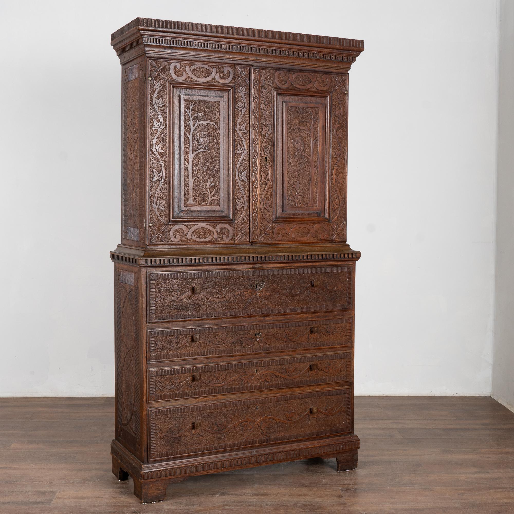 Elaborate carving accentuate the entire surface of this striking pine secretary.
Enlarge photos to appreciate the extensive details, including vines, birds, leaves, trees, dentil molding and more.
The middle section is the traditional desk which